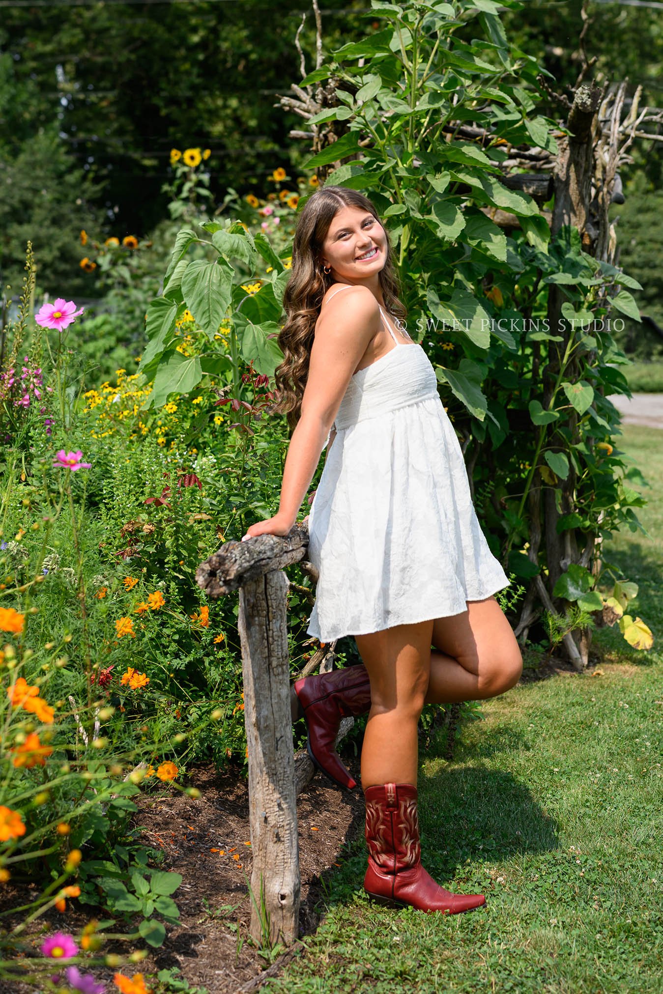 Zionsville, Indiana Country Senior Portrait Photography at Traders Point Creamery with class of 2027 senior girl posing in white dress and red western boots in country garden by Sweet Pickins Studio senior photographer Amanda Wilson ©