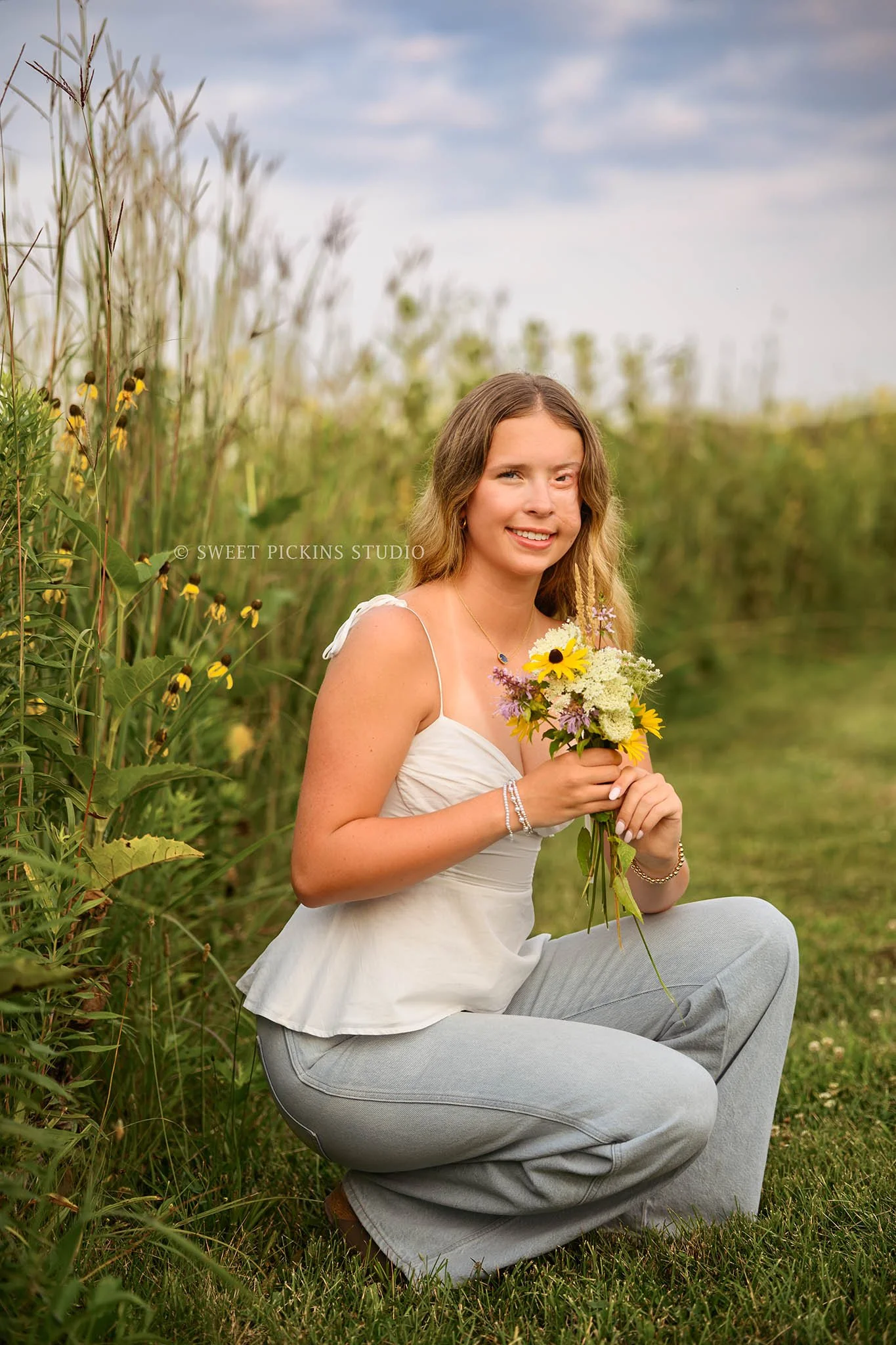 Kilyn’s Noblesville, Indiana Summer Senior Photography for class of 2027 senior girl wearing white tank and denim jeans in flower field location with bouquet by Sweet Pickins Studio senior photographer Amanda Wilson ©