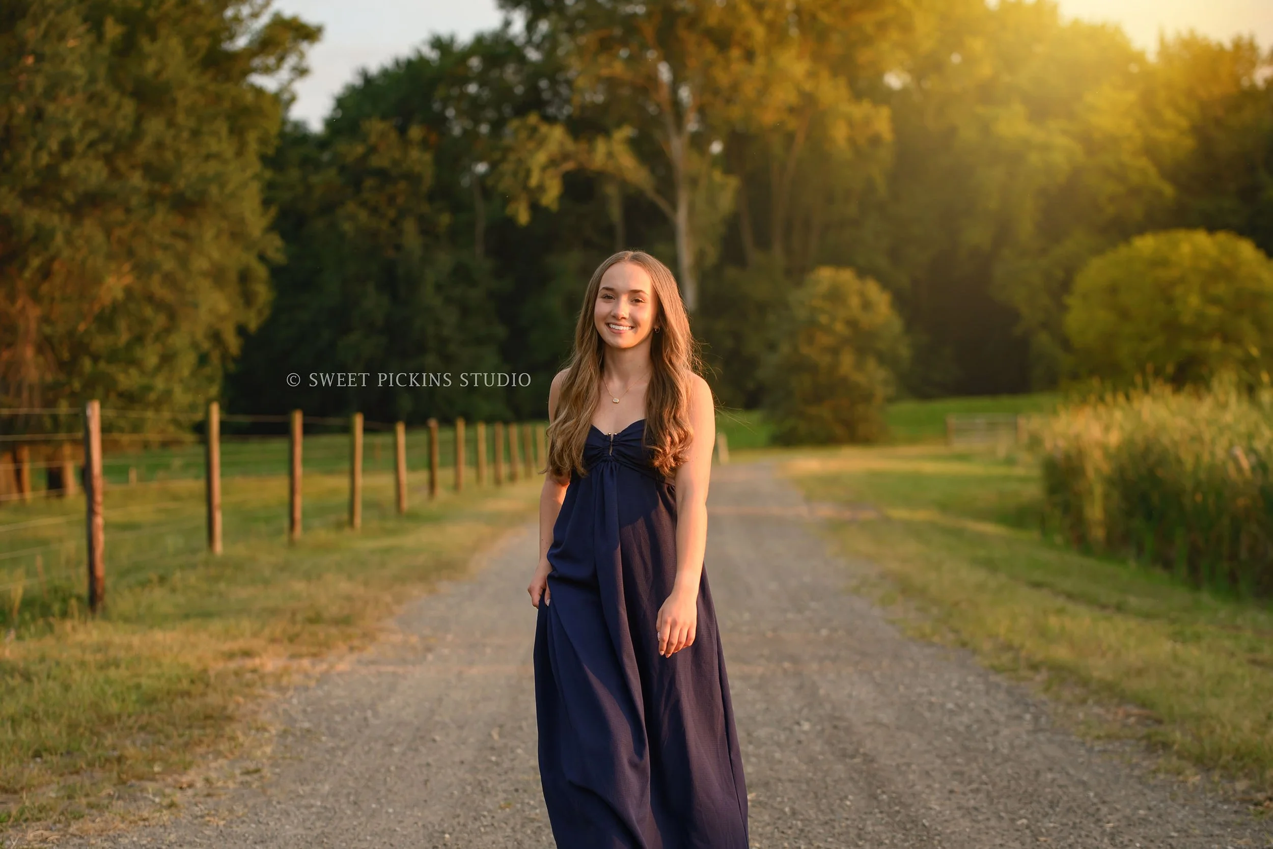 Natalie’s Lowell, Indiana Senior Photography posing on dirt lane by fence on farm at sunset by Sweet Pickins Studio senior photographer Amanda Wilson ©