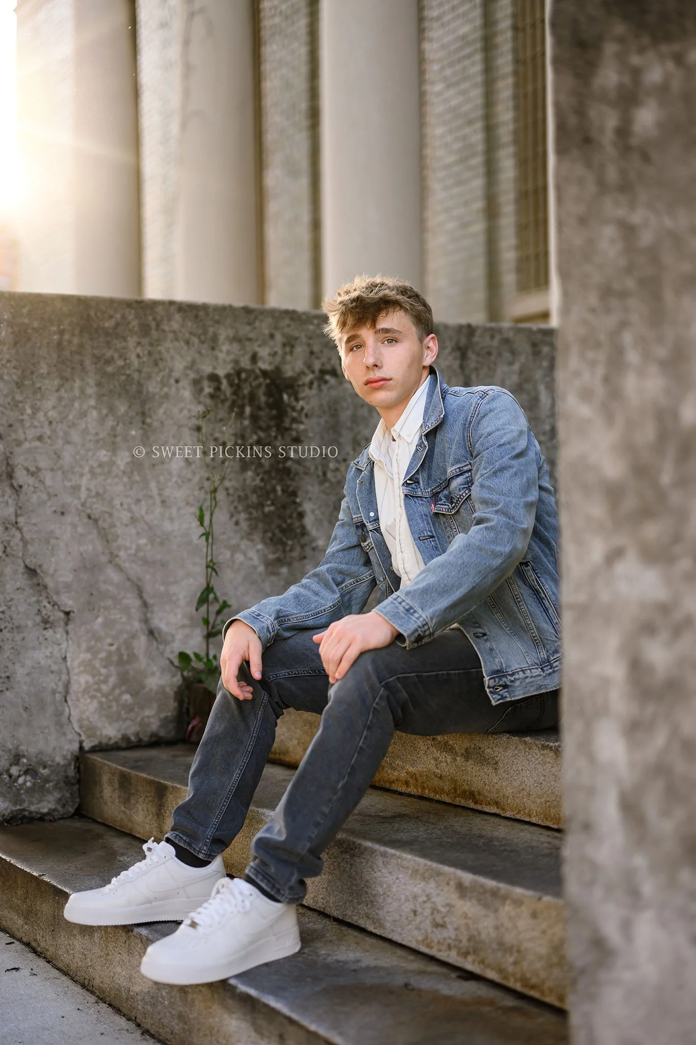 Huntington, Indiana Senior Guy Photography for Huntington North Class of 2027 Senior boy BOSTAN sitting on concrete steps in denim jean jacket in urban downtown by Sweet Pickins Studio senior photographer Amanda Wilson ©
