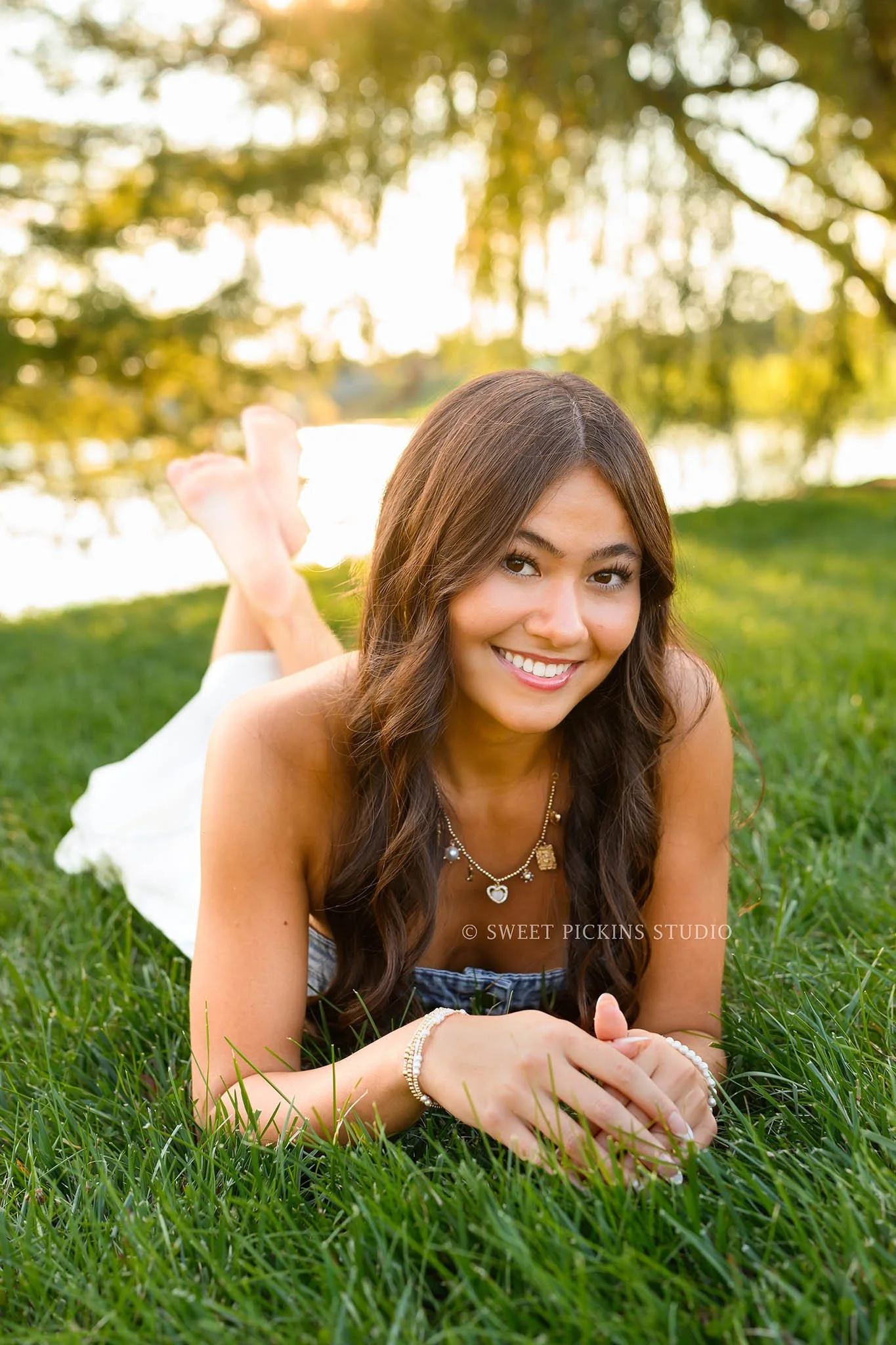 Rachel | Carmel, Indiana Senior Photography at golden hour for Class of 2027 senior girl wearing denim crop top and white skirt lying in grass by Sweet Pickins Studio senior photographer Amanda Wilson ©