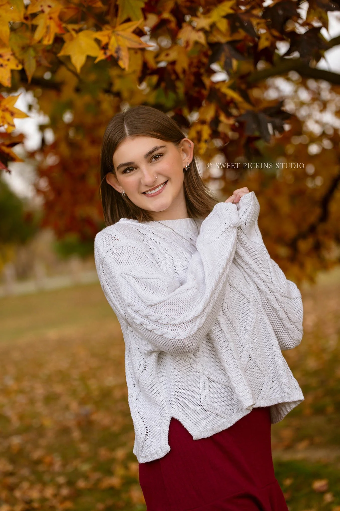 Torre’s Kokomo, Indiana Fall Senior Photography for Kokomo High School Class of 2026 senior girl wearing sweater and skirt in fall tree leaves by Sweet Pickins Studio senior photographer Amanda Wilson ©