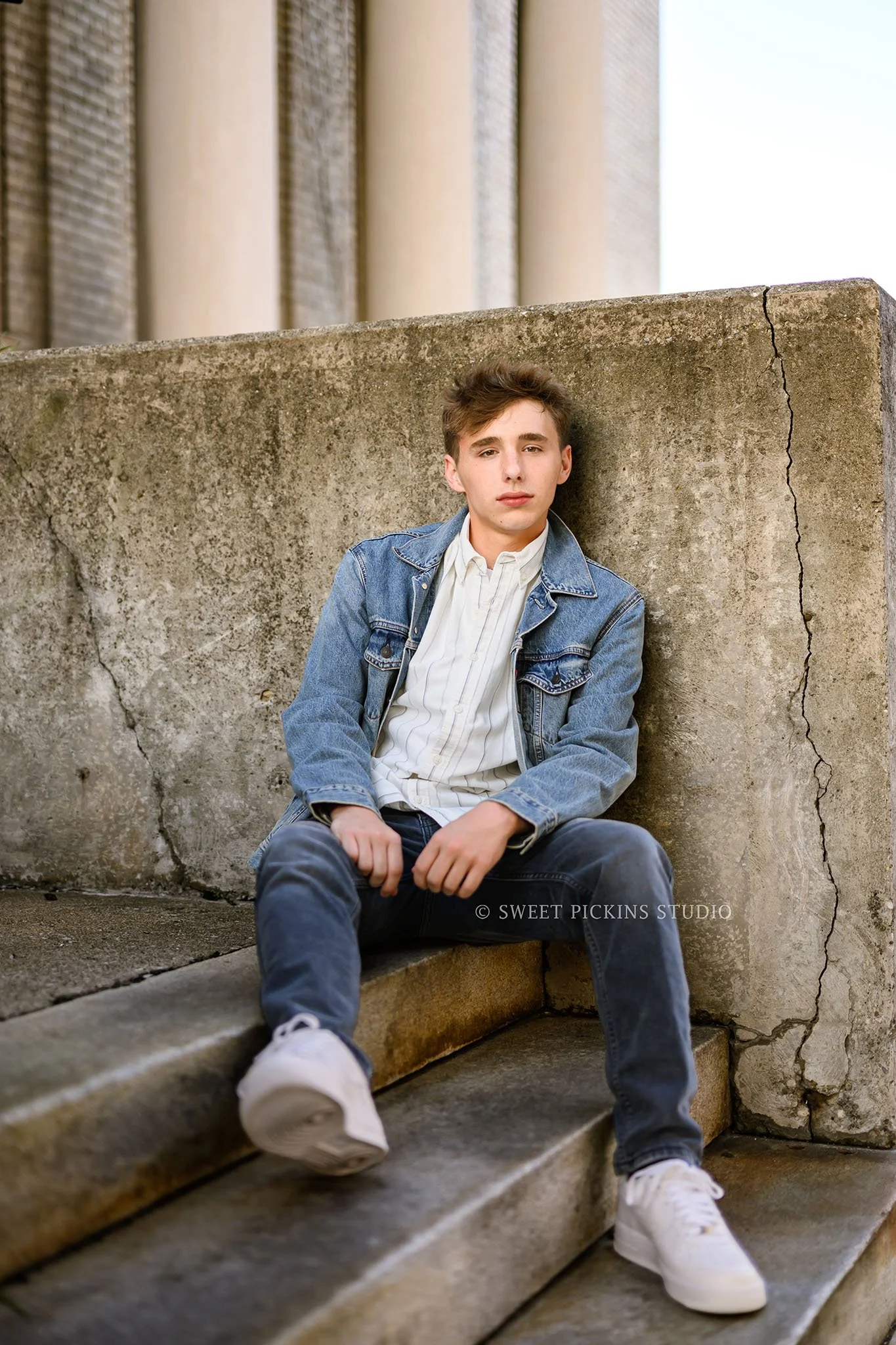 Huntington, Indiana Senior Guy Photography for Huntington North Class of 2027 Senior boy BOSTAN sitting on concrete steps in denim jean jacket in urban downtown by Sweet Pickins Studio senior photographer Amanda Wilson ©