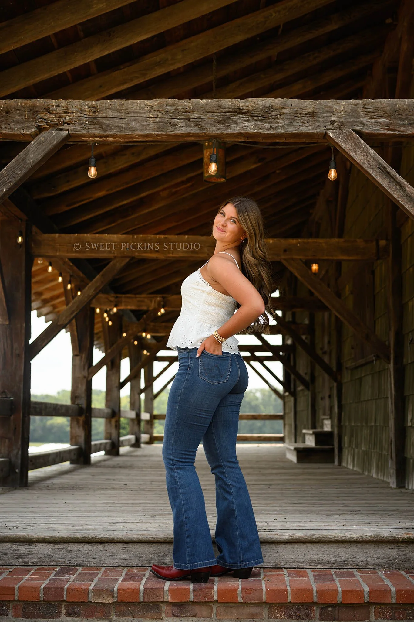 Zionsville, Indiana Senior Portrait Photography at Traders Point Creamery with class of 2027 senior girl wearing denim jeans and red western boots at barn by Sweet Pickins Studio senior photographer Amanda Wilson ©