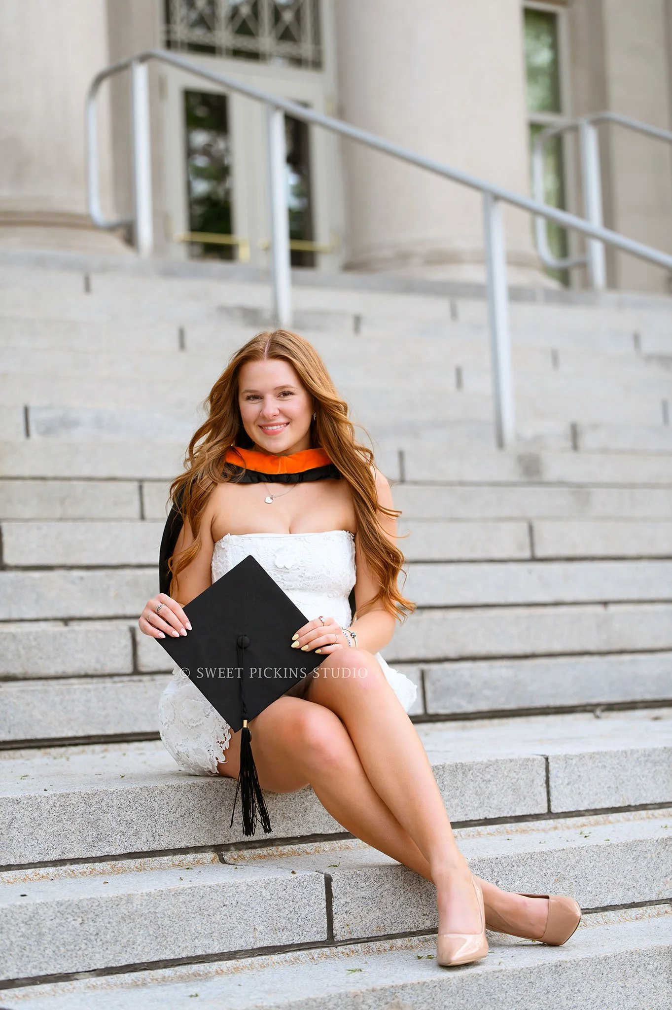 Lauren’s Purdue Graduation Photography in West Lafayette, Indiana by Sweet Pickins Studio photographer Amanda Wilson for spring graduate posing in white dress at Hovde Hall steps with grad cap and tassel © 2026