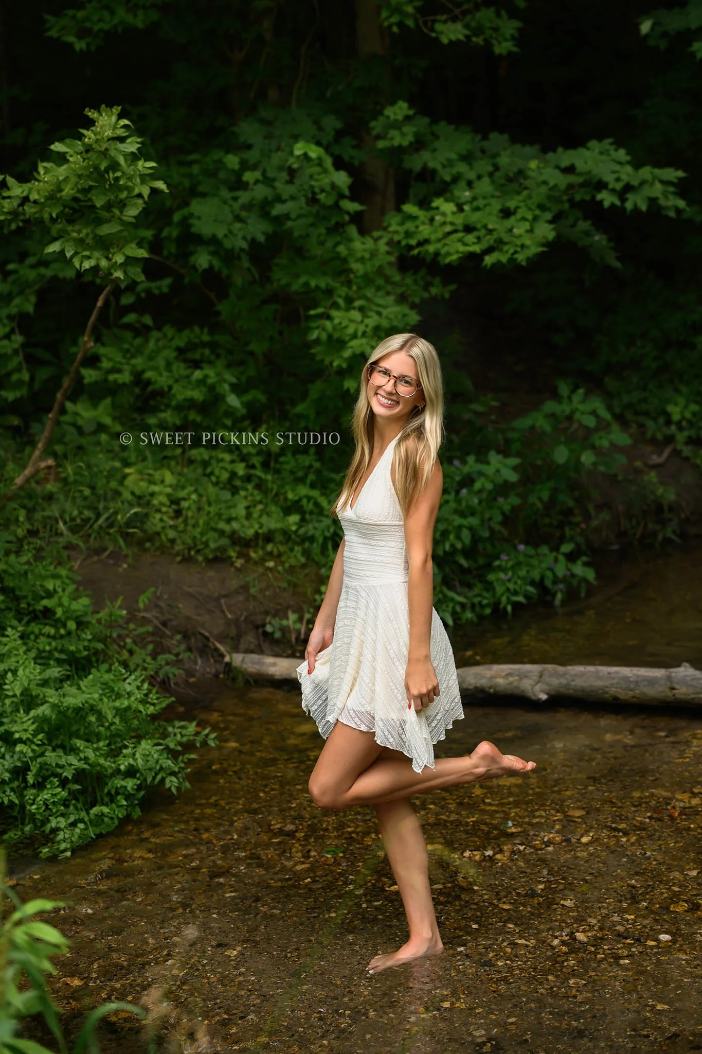 Kyree’s Creek Senior Photography in Peru, Indiana for Logansport High School Class of 2027 senior girl wearing white dress in creek water in forest by Sweet Pickins Studio senior photographer Amanda Wilson ©
