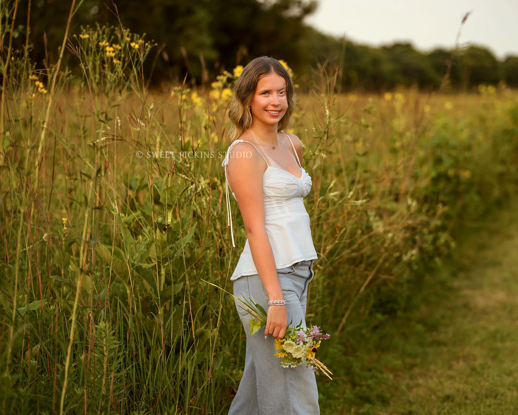 Kilyn’s Noblesville, Indiana Summer Senior Photography for class of 2027 senior girl wearing white tank and denim jeans in flower field location with bouquet by Sweet Pickins Studio senior photographer Amanda Wilson ©