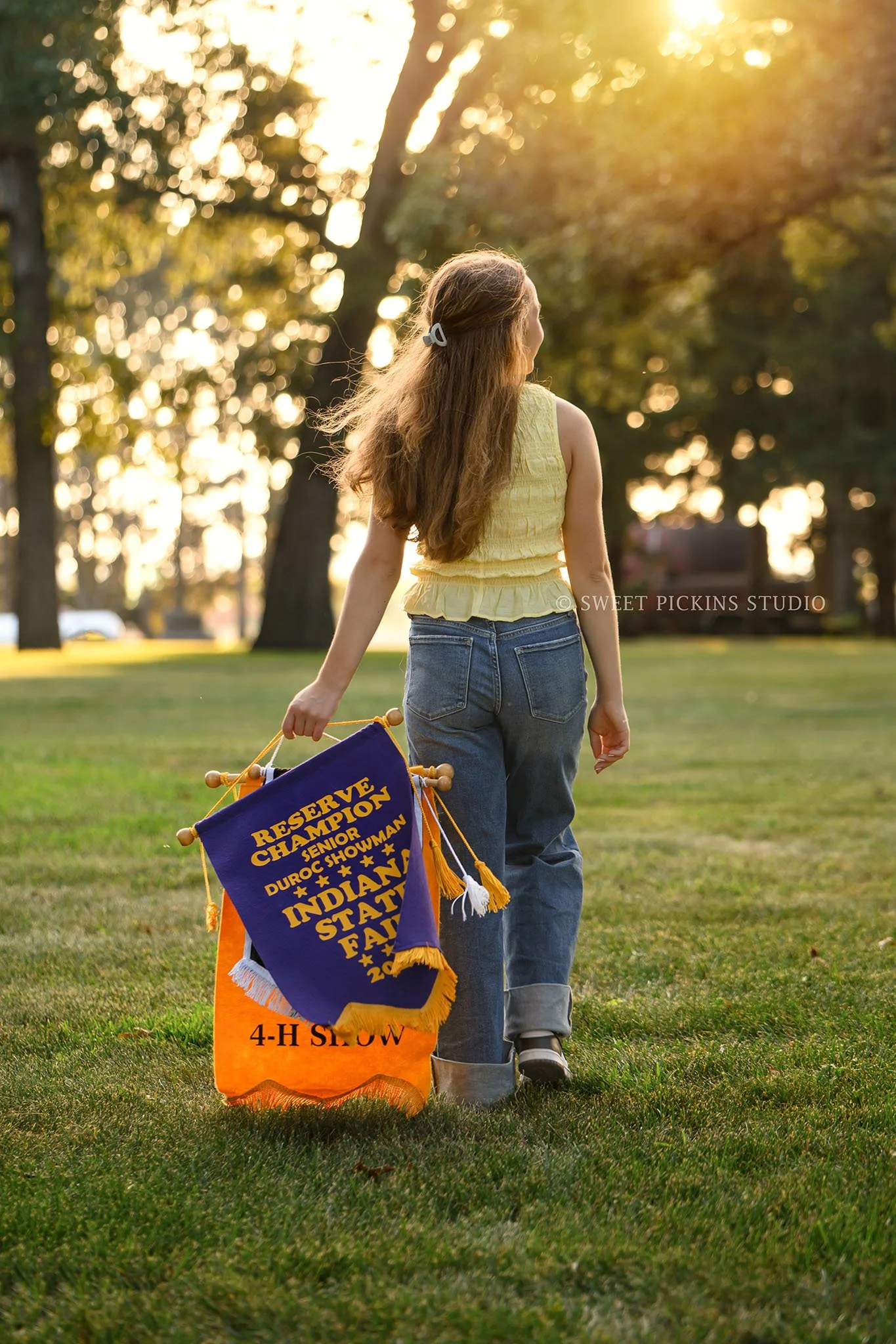 Natalie’s Lowell, Indiana 4-H Senior Photography for class of 2027 senior girl posing with livestock show banners at family farm by Sweet Pickins Studio senior photographer Amanda Wilson ©