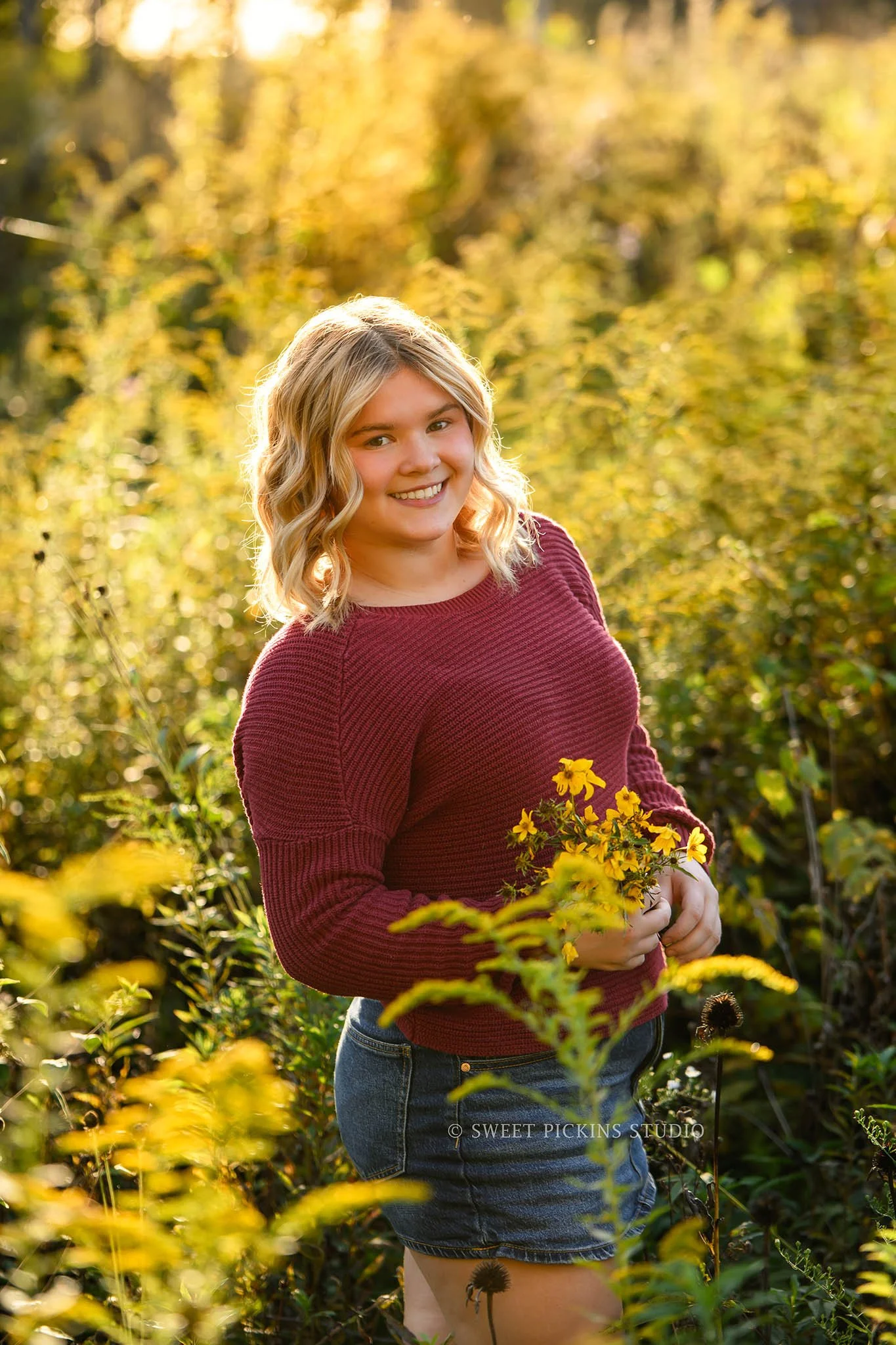 Rilynn’s Peru, Indiana Fall Senior Portrait Photography in yellow flowers for Maconaquah High School class of 2027 senior girl wearing maroon sweater and denim skirt by Sweet Pickins Studio senior photographer Amanda Wilson ©