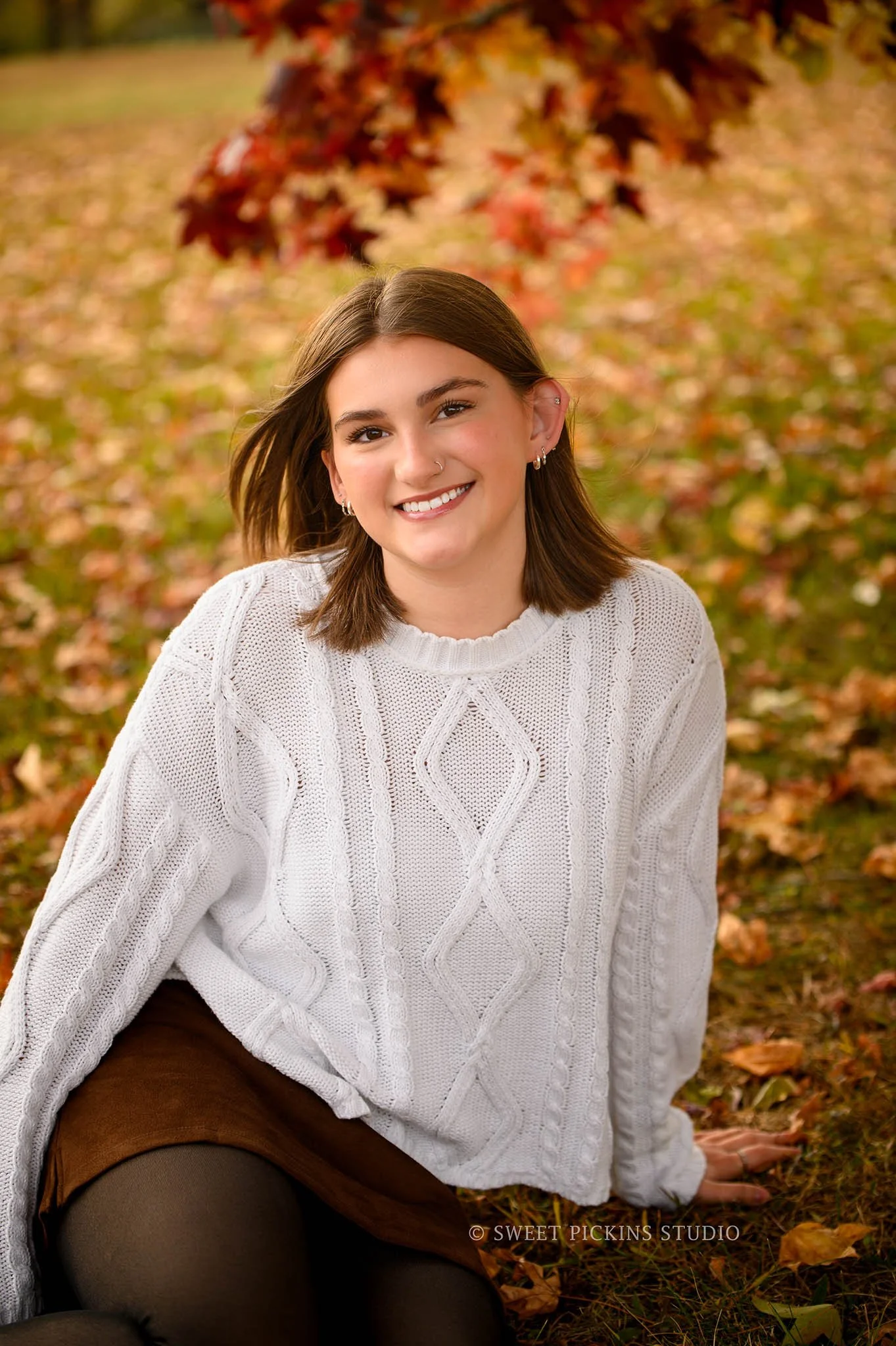 Torre’s Kokomo, Indiana Fall Senior Photography for Kokomo High School Class of 2026 senior girl wearing sweater and skirt in fall tree leaves by Sweet Pickins Studio senior photographer Amanda Wilson ©