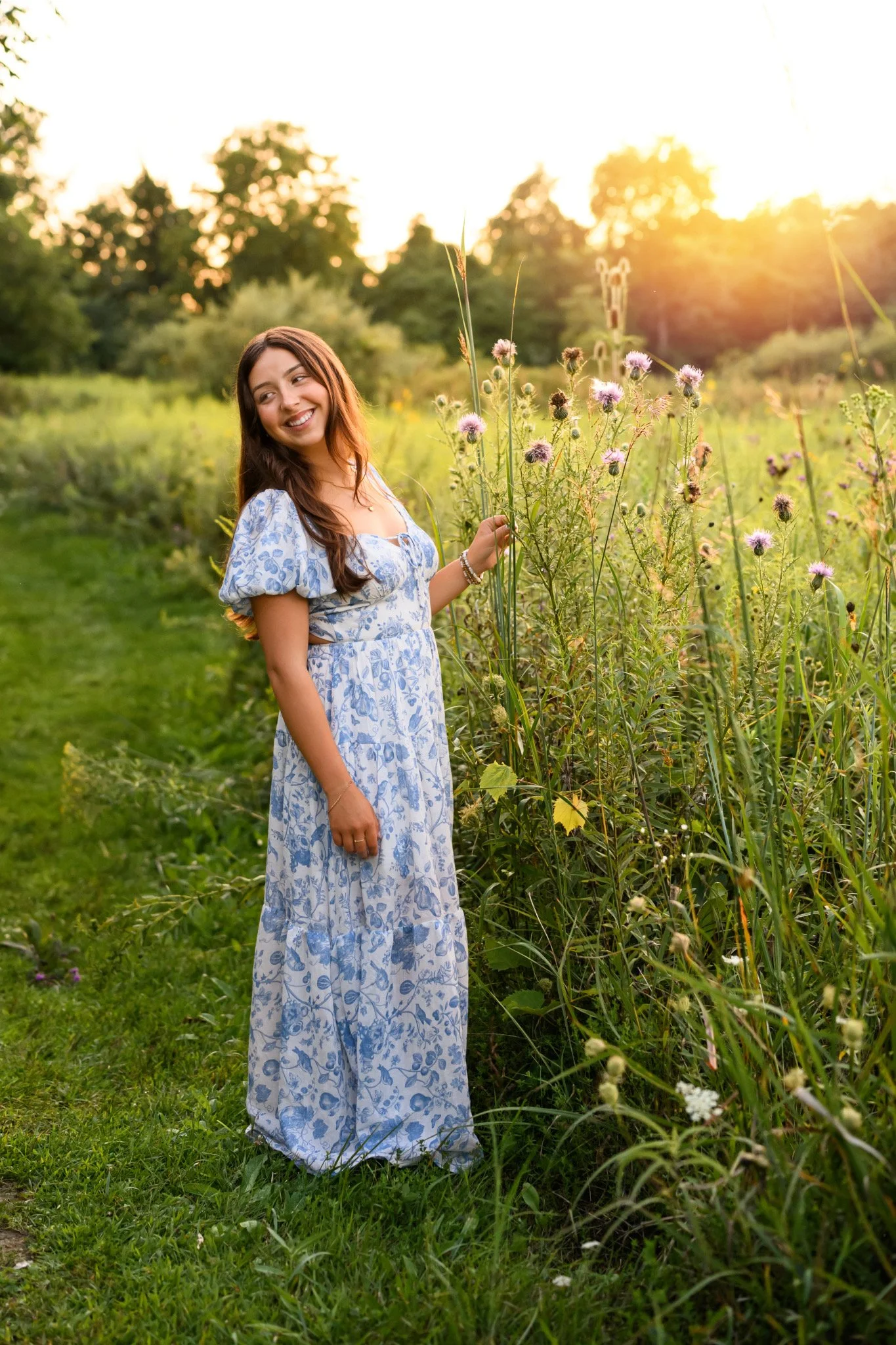 Maisie | Lakeville, Indiana Senior Photography in Field at Sunset for Madison East High School class of 2027 senior girl posing in blue floral dress with wildflowers by Peru Indiana senior photographer Amanda Wilson © Sweet Pickins Studio