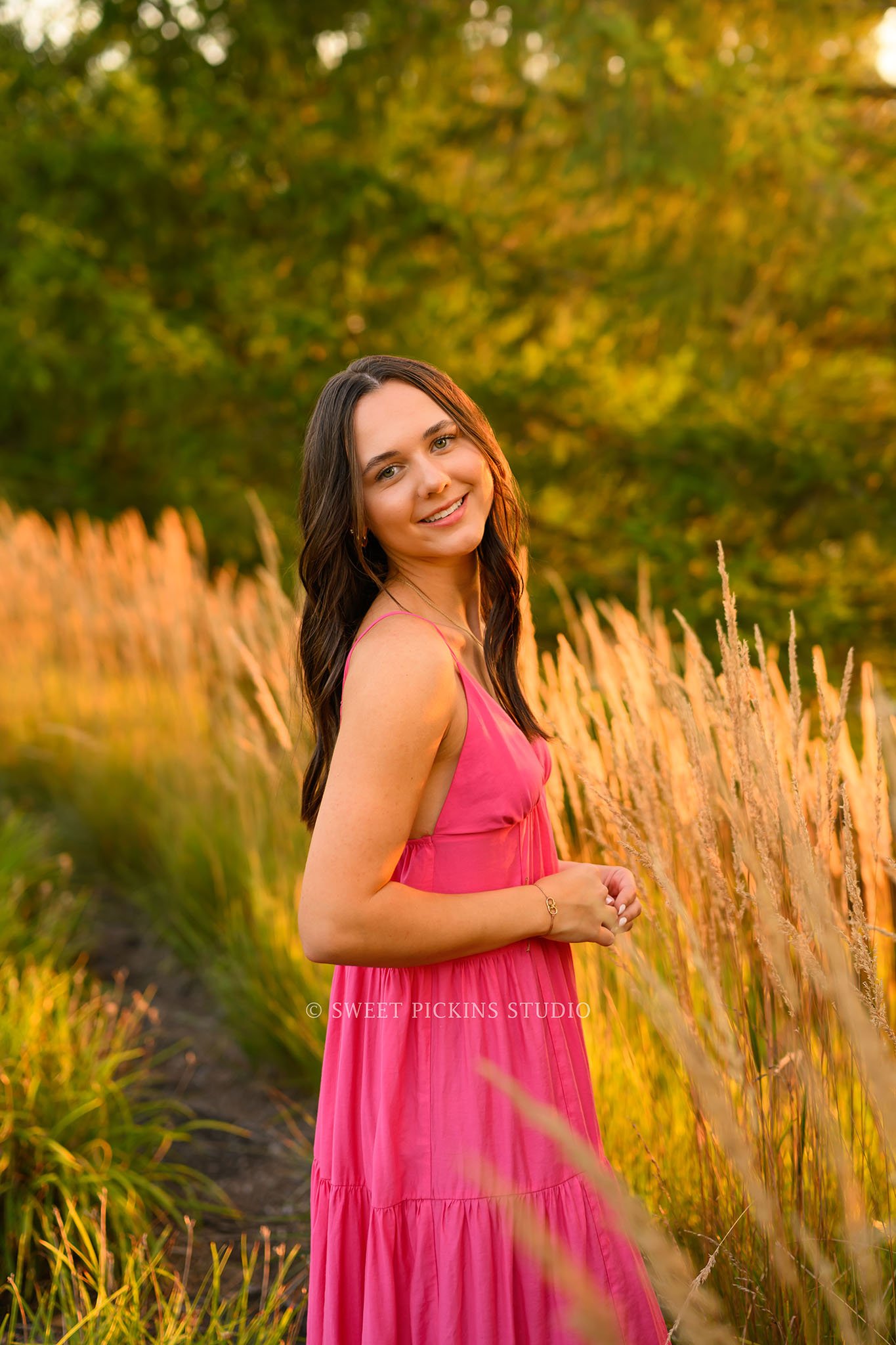 Sophie’s Carmel, Indiana Senior Photography by Sweet Pickins Studio senior photographer Amanda Wilson for class of 2027 Senior girl posing in pink maxi dress in golden grass at sunset ©