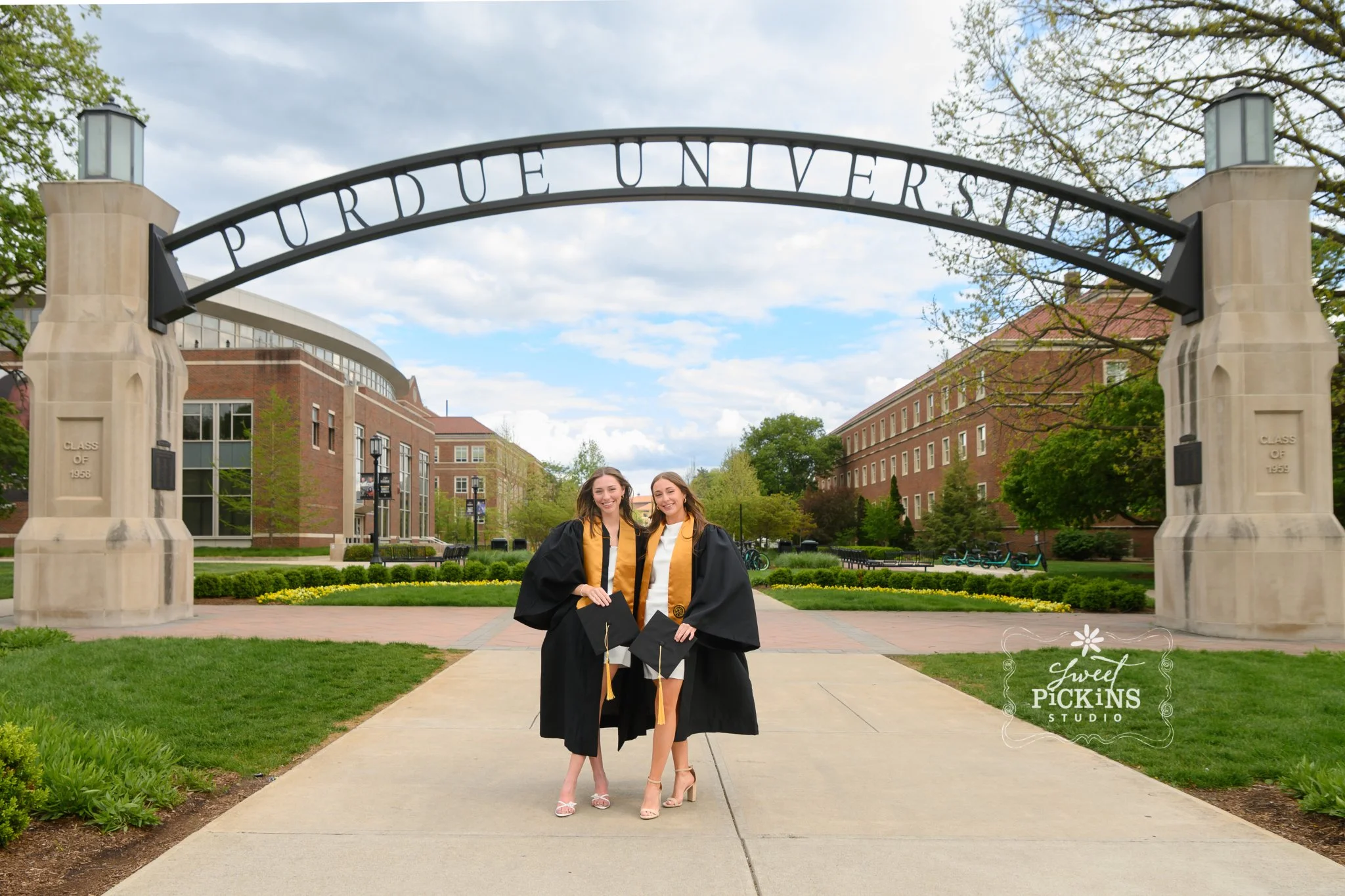 Purdue University Graduation Photography for Twins Class of 2026 Sisters pose at Engineering  arch in West Lafayette, Indiana by Sweet Pickins Studio senior photographer Amanda Wilson ©
