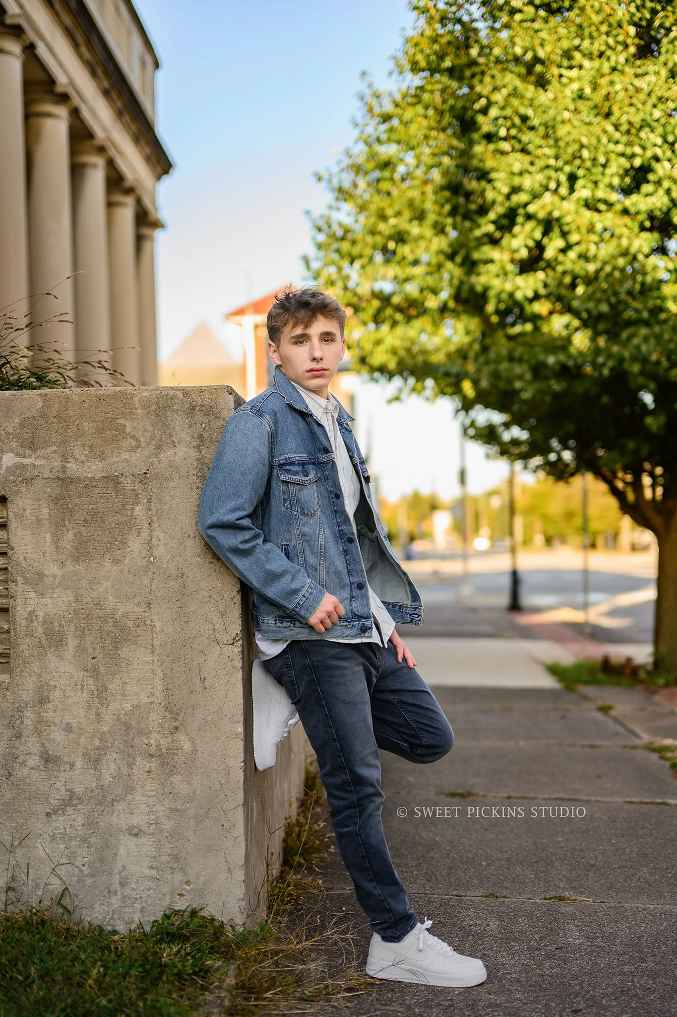 Huntington, Indiana Fall Senior Portraits for Huntington North Class of 2027 Senior Guy BOSTAN posing in denim jean jacket by concrete wall in urban downtown by Sweet Pickins Studio senior photographer Amanda Wilson ©