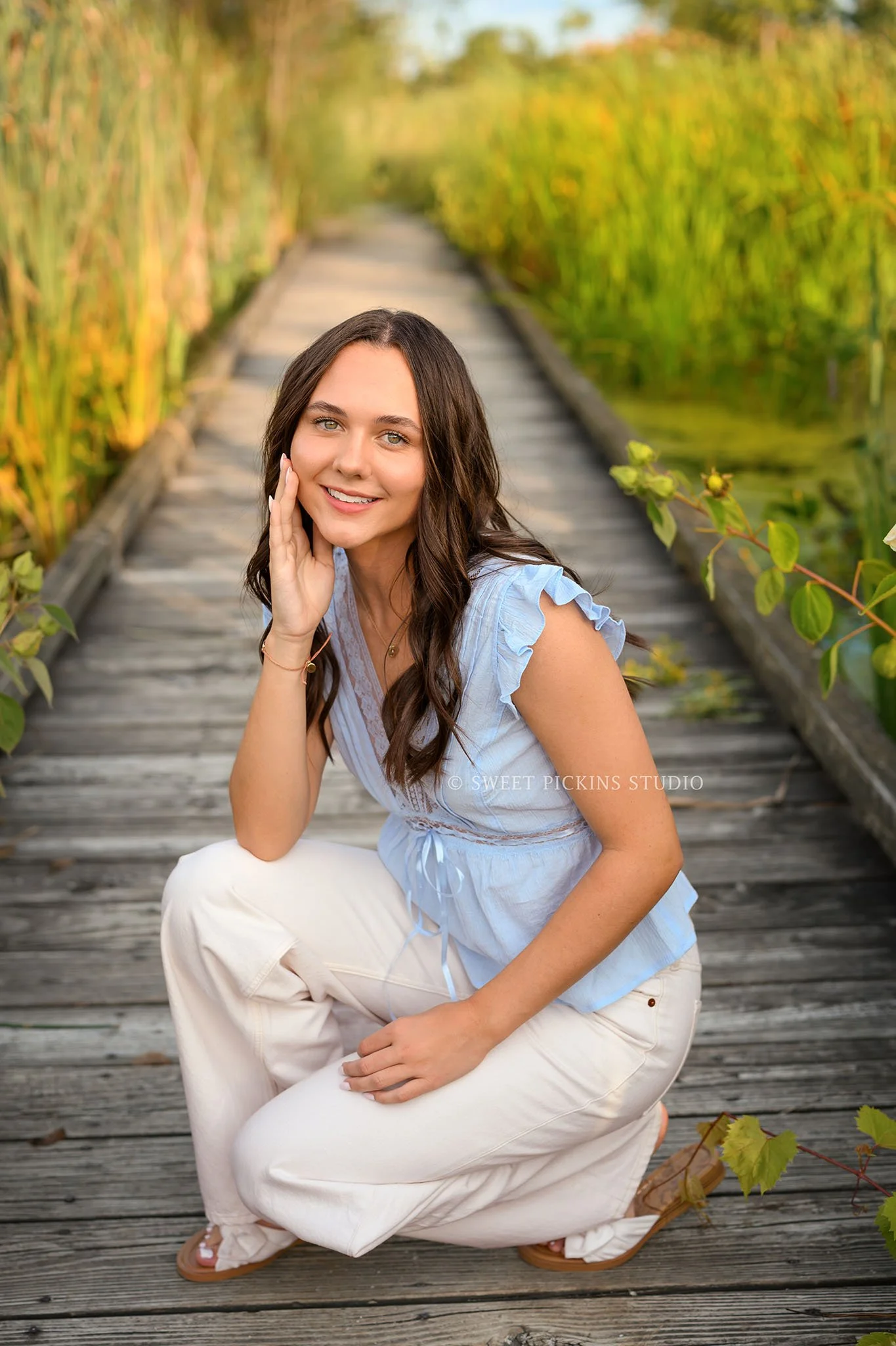 Sophie’s Carmel, Indiana Senior Portrait Photography by Sweet Pickins Studio senior photographer Amanda Wilson for class of 2027 Senior girl posing in blue eyelet top and white jeans in flower field at golden hour ©