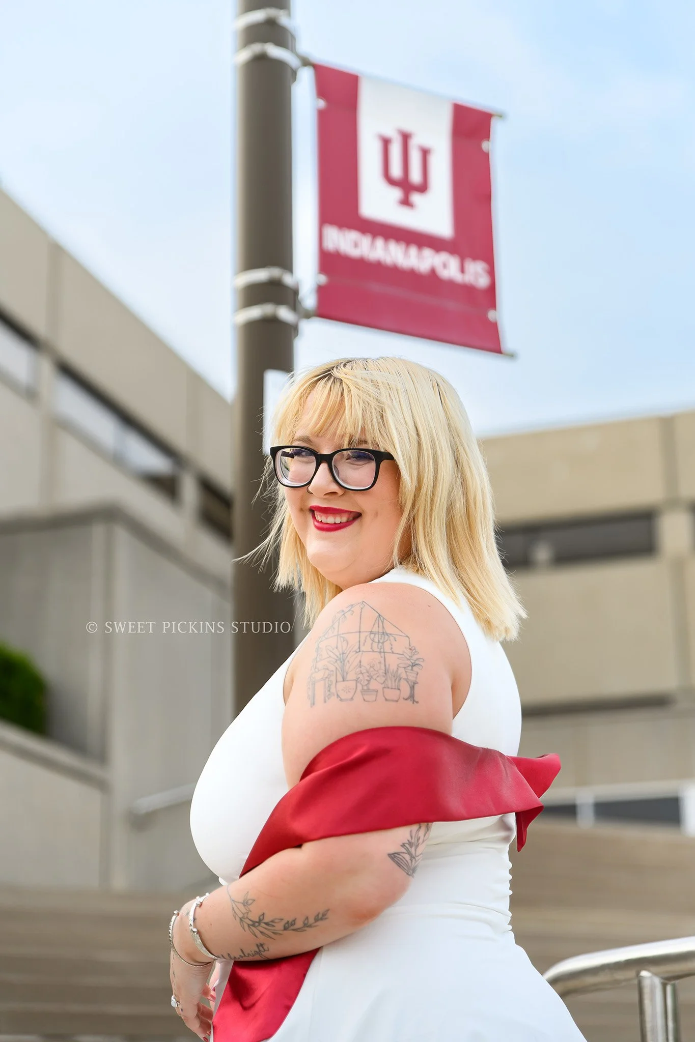 Indianapolis, Indiana Graduation Photography for IU Indy class of 2026 spring grad wearing red stole and white dress on campus by Sweet Pickins Studio senior photographer Amanda Wilson ©
