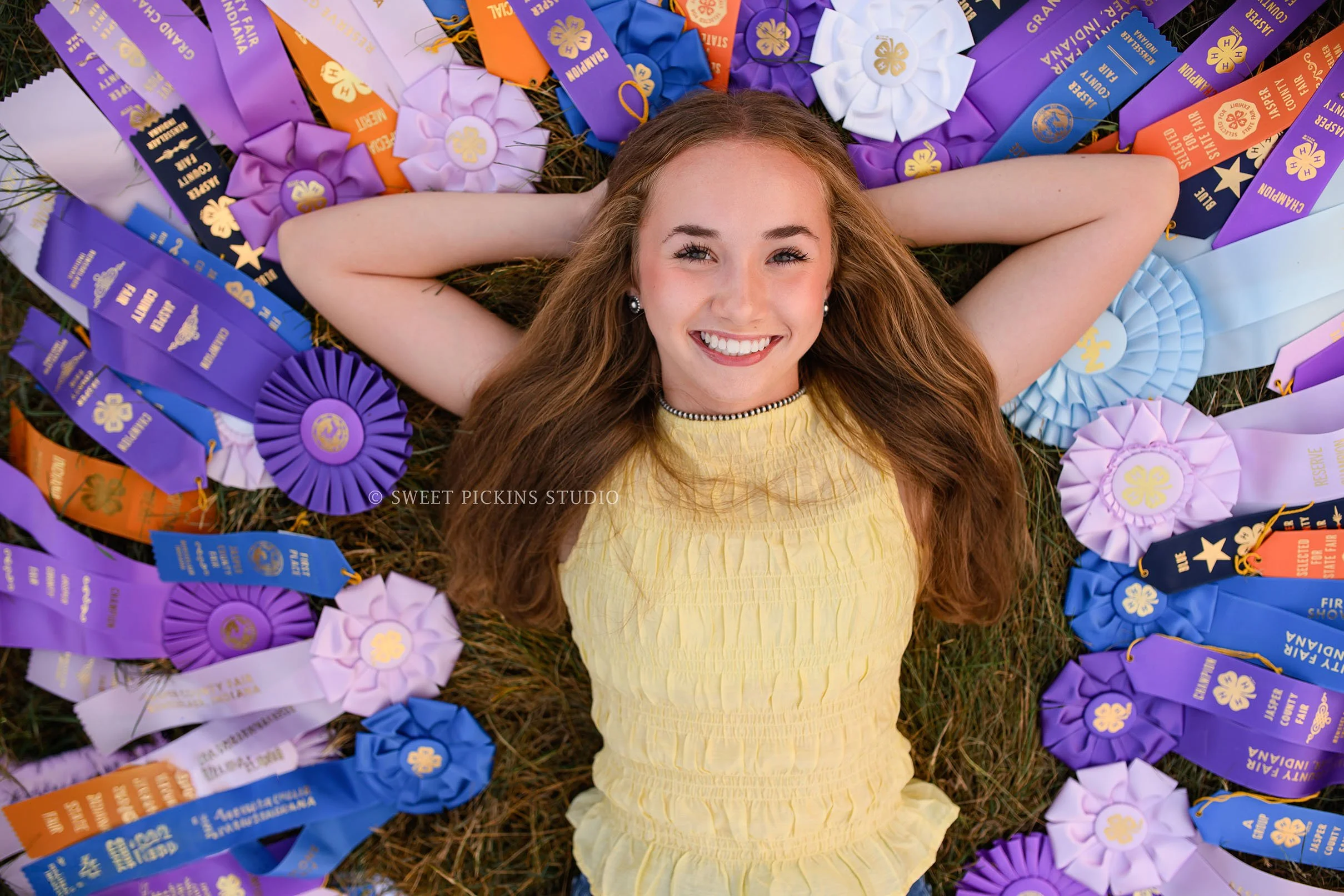 Natalie’s Lowell, Indiana Floral Senior Photography for class of 2027 senior girl posing with colorful 4-H show ribbons at  family farm by Sweet Pickins Studio senior photographer Amanda Wilson ©