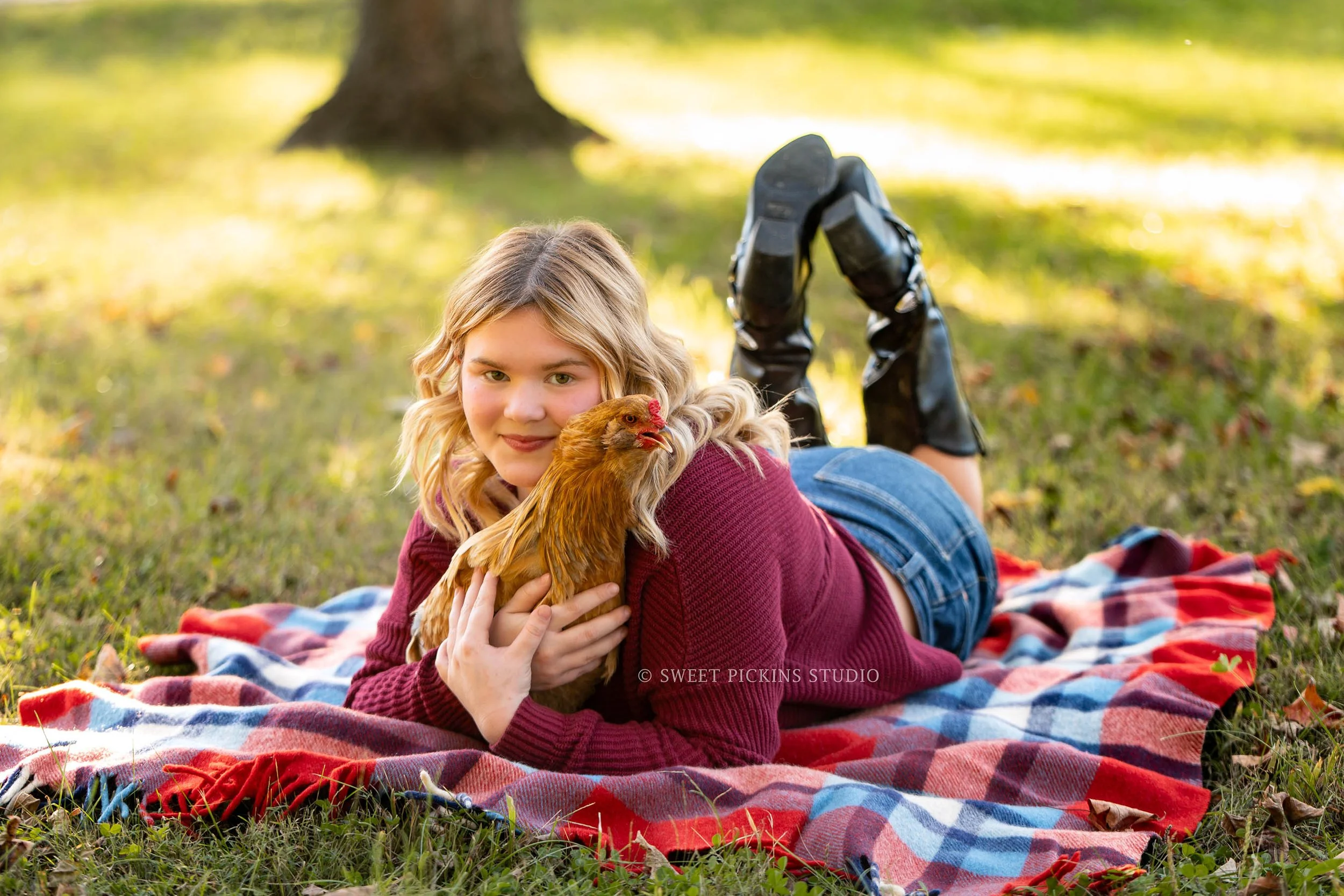 Rilynn’s Peru, Indiana Fall Senior Portrait Photography with pet chicken for Maconaquah High School class of 2027 senior girl wearing maroon sweater and denim skirt on plaid blanket by Sweet Pickins Studio senior photographer Amanda Wilson ©