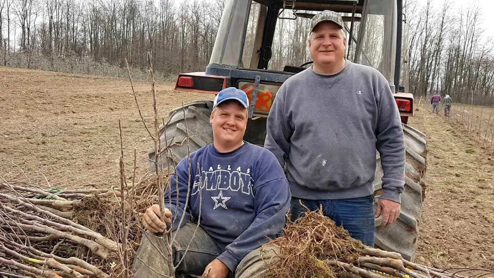Twin Bee Orchard co-owner Tony Blattner and his son Nathan, left, take a break while planting 4,600 Smitten trees in spring 2016. Twin Bee, in west-central Michigan, has 135 acres of apples, including Gala, Red Delicious, Fuji, Honeycrisp, McIntosh, Empire, Ida Red and Jonagolds. Photo by Twin Bee Orchard LLC.