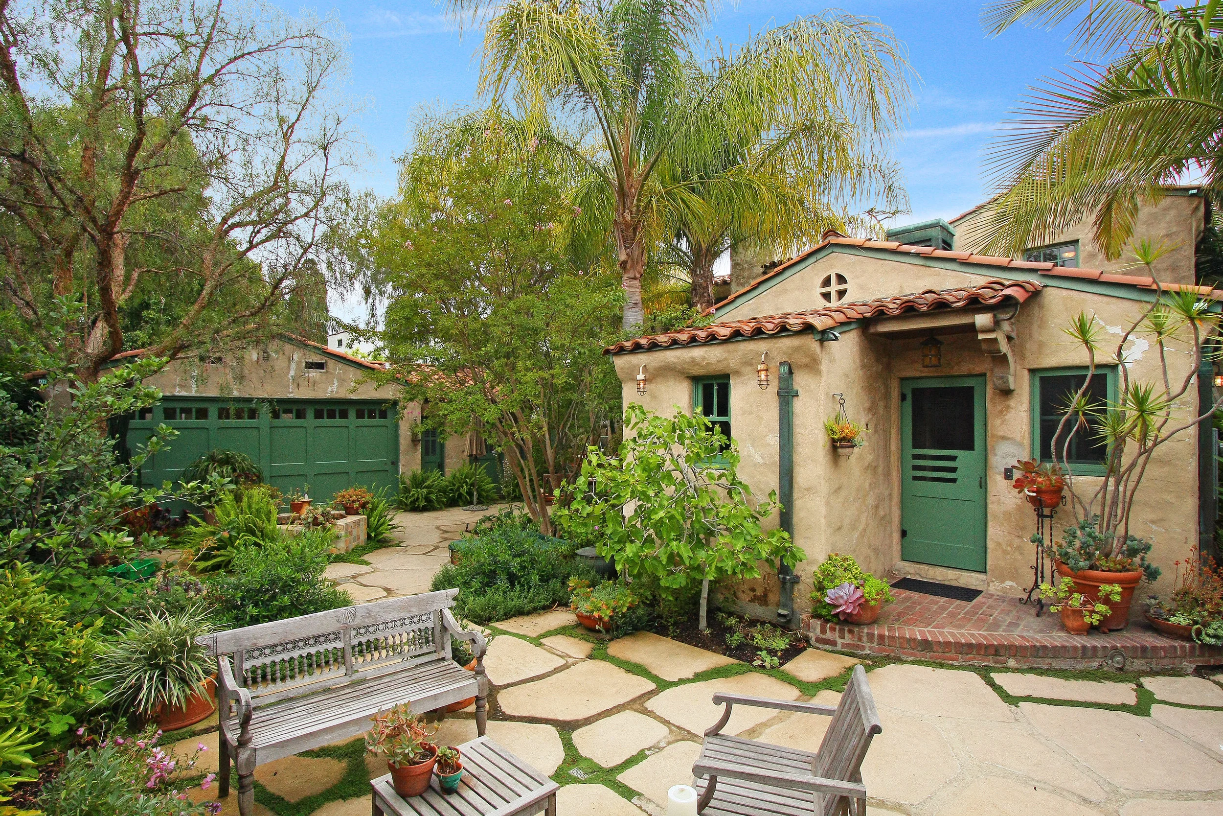 Original garage doors restored. Wrap around driveway removed to make space for new exterior rooms & garden. 
