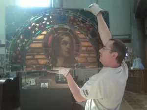 Pictured here holding a section of the St. John the Evangelist window is Colin Albig of Images in Glass which is located in Hamburg, New York. Images in Glass did the restoration and installation.