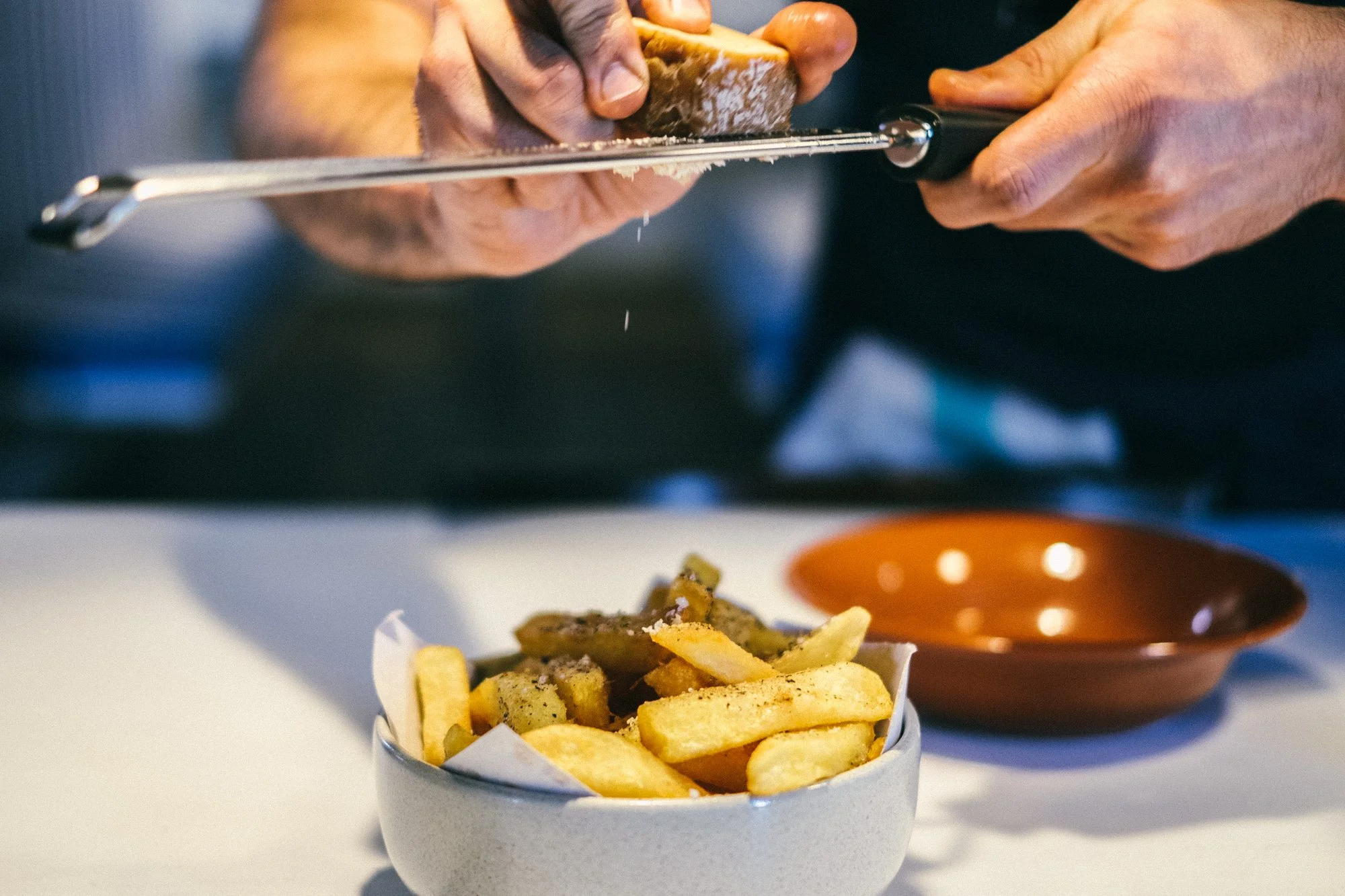 Aquele momento épico em que Bruno rala o toucinho curado sobre as batatas fritas da casa. (foto: © Tiago Pais / Observador)