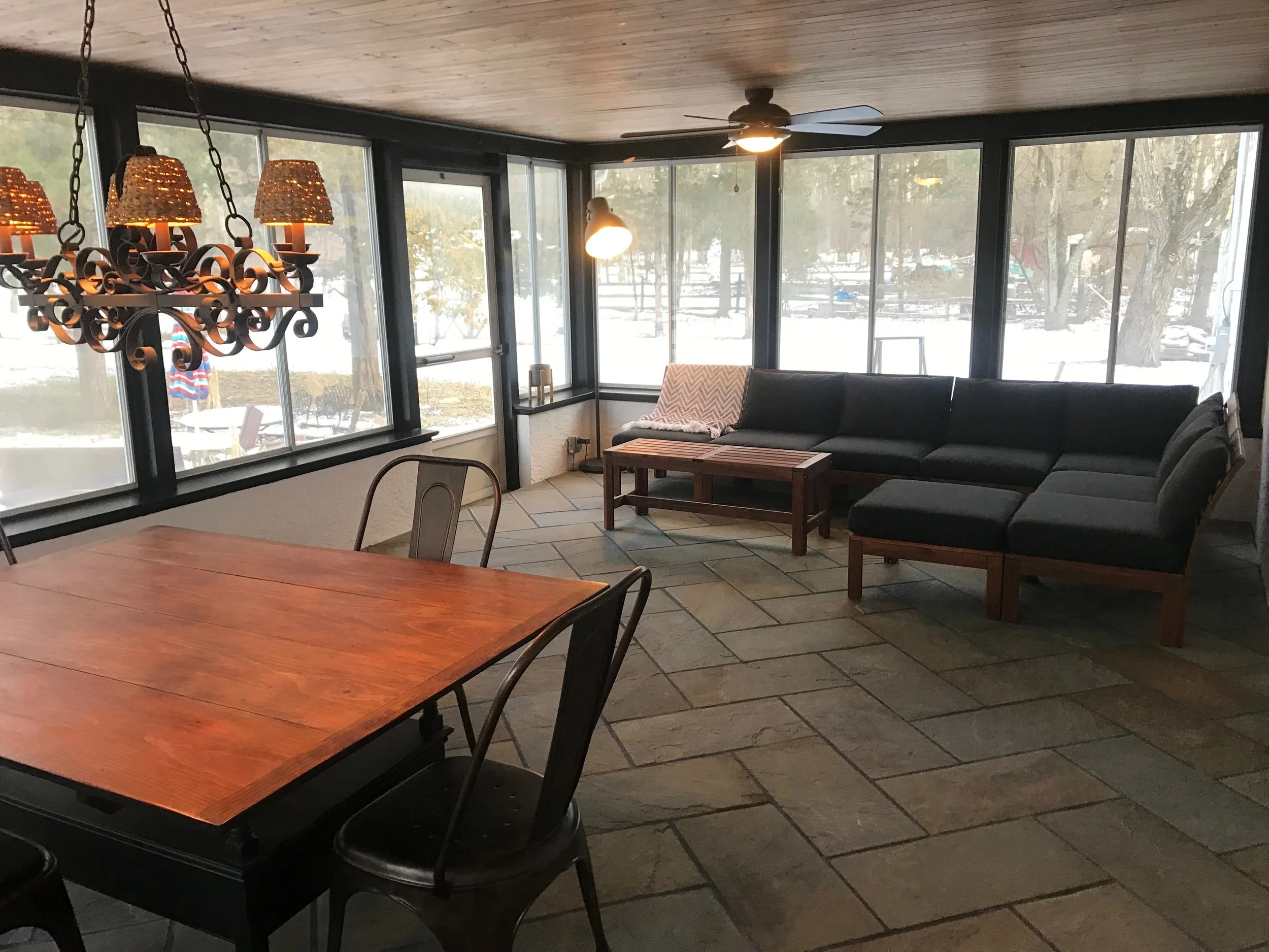 After we completed the floors and stained the ceiling, we installed a chandelier and a fan. The previous owners had two fans, but we wanted to create a separate "living" and "dining" area, and thought that a chandelier would be beautiful above a table that we had been holding onto for the room. Next we added the furniture - dining table and chairs and an outdoor couch.