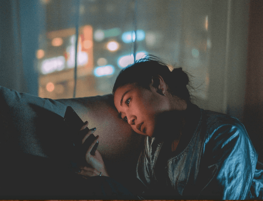 asian woman looking on phone upset on couch and going through breakup in nyc