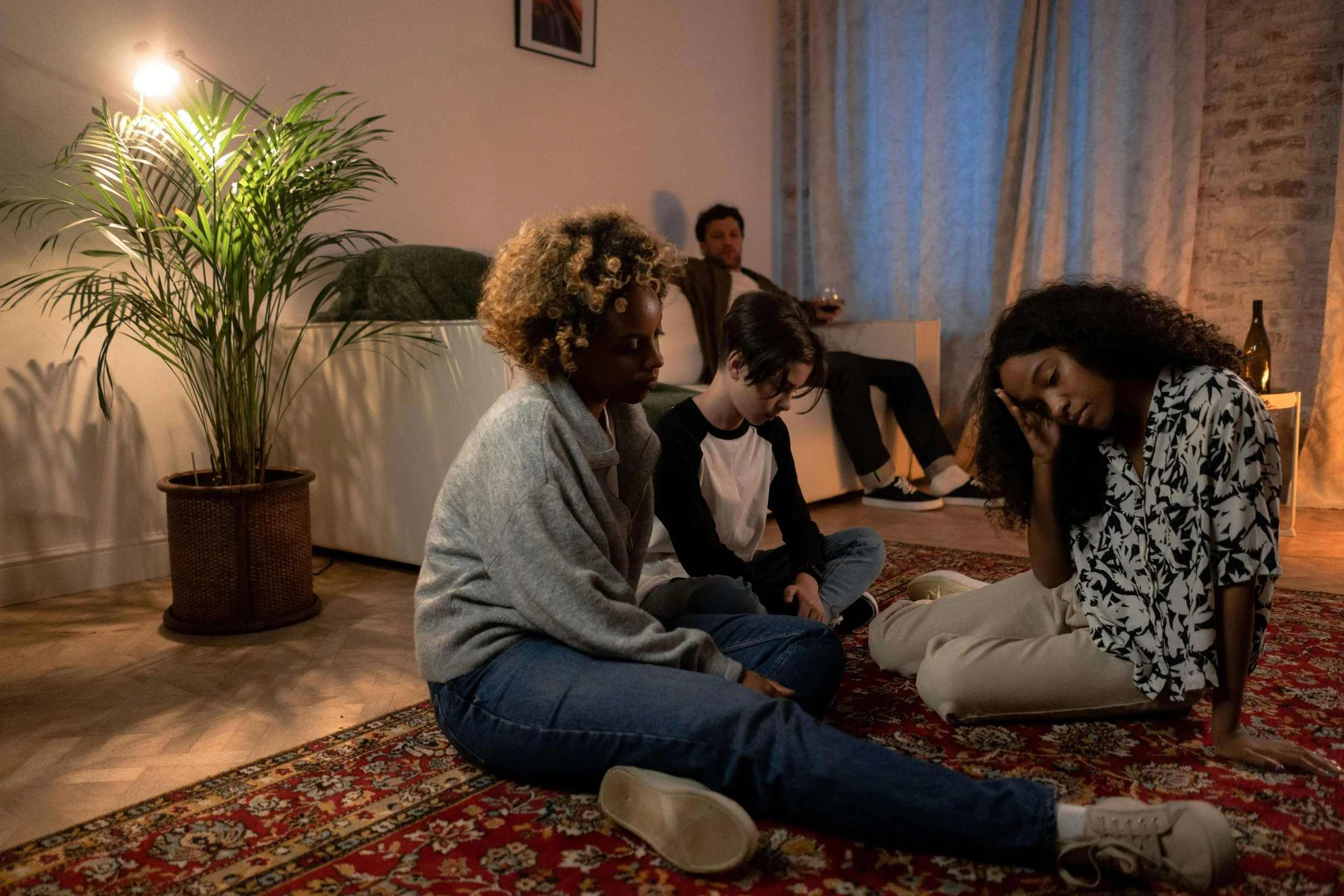 An upset family sitting on the floor amid the tension and dysfunction that can create a family scapegoat, from a Hoboken NJ therapist