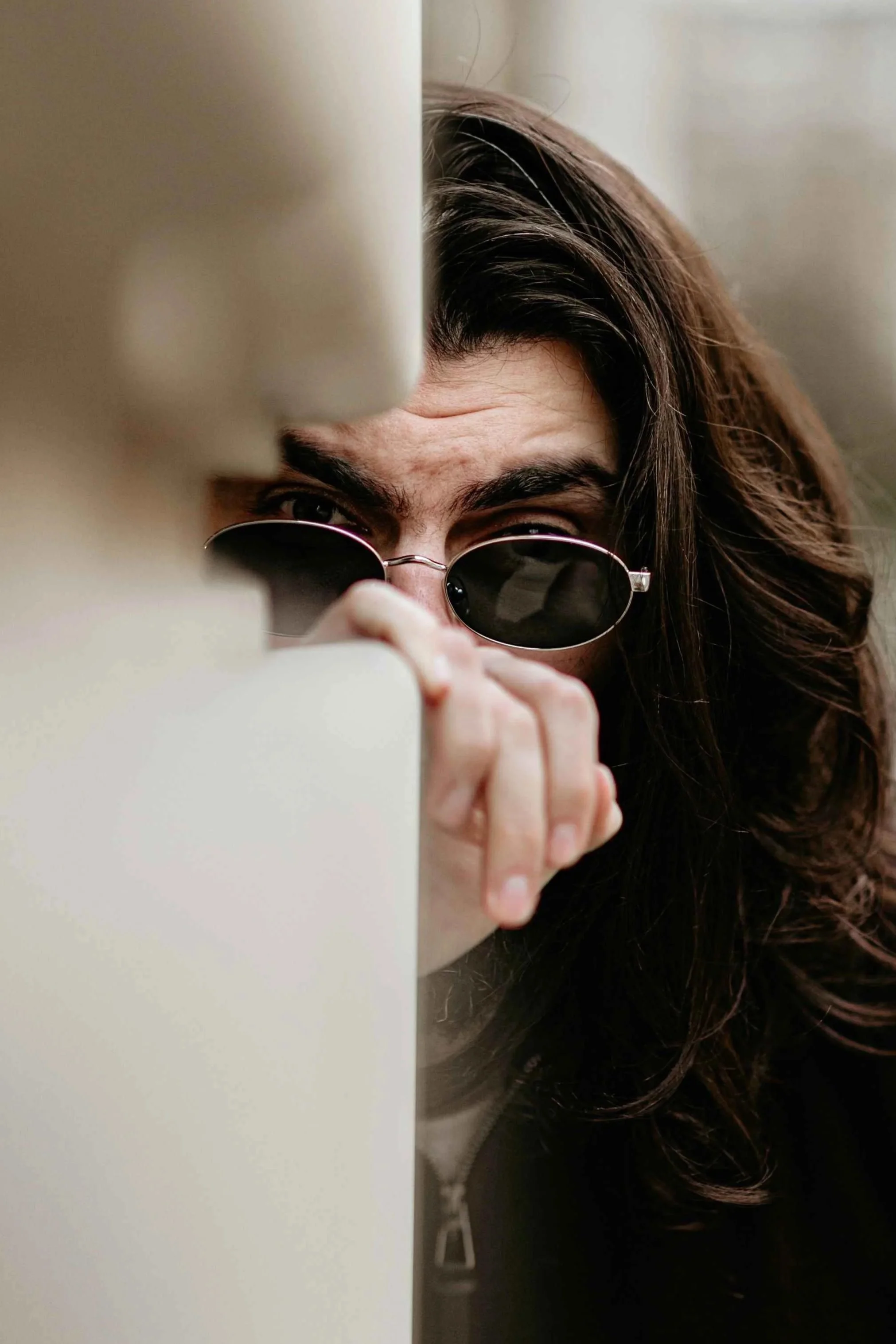 Person peering guardedly from behind a wall, an example of the hidden, watchful side of a covert narcissist, Hoboken NJ therapist