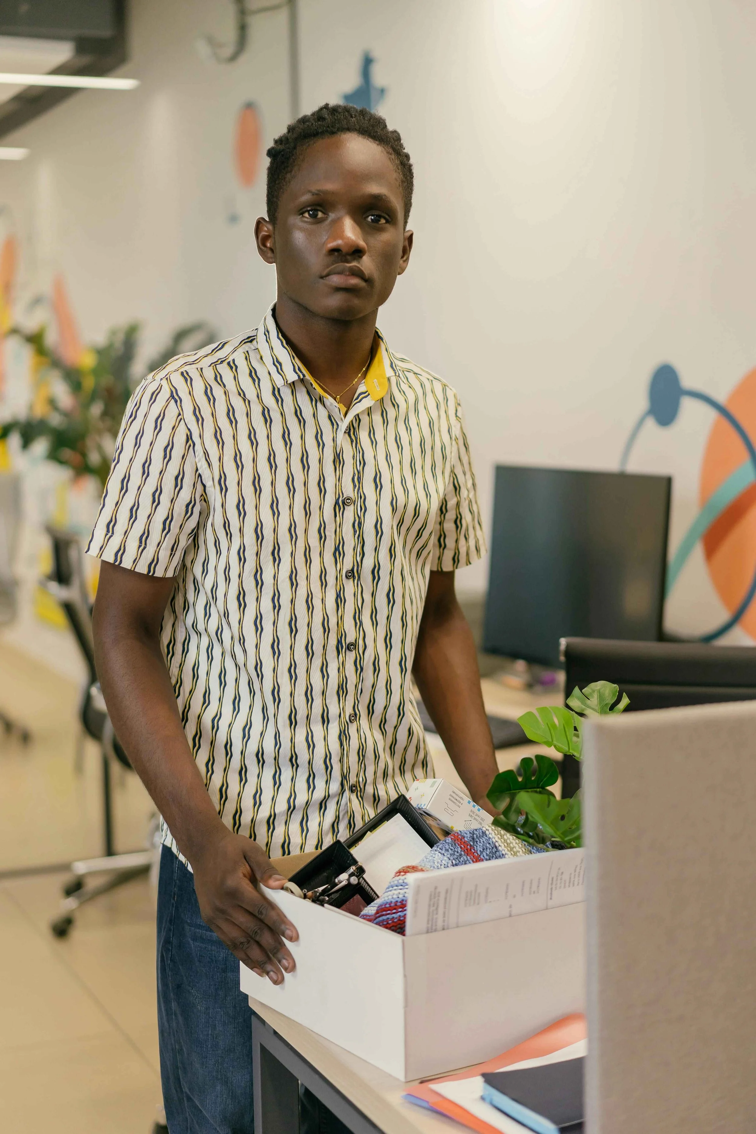 A man carrying his belongings in a box while leaving his office, experiencing anxiety and emotional stress after an unexpected job loss