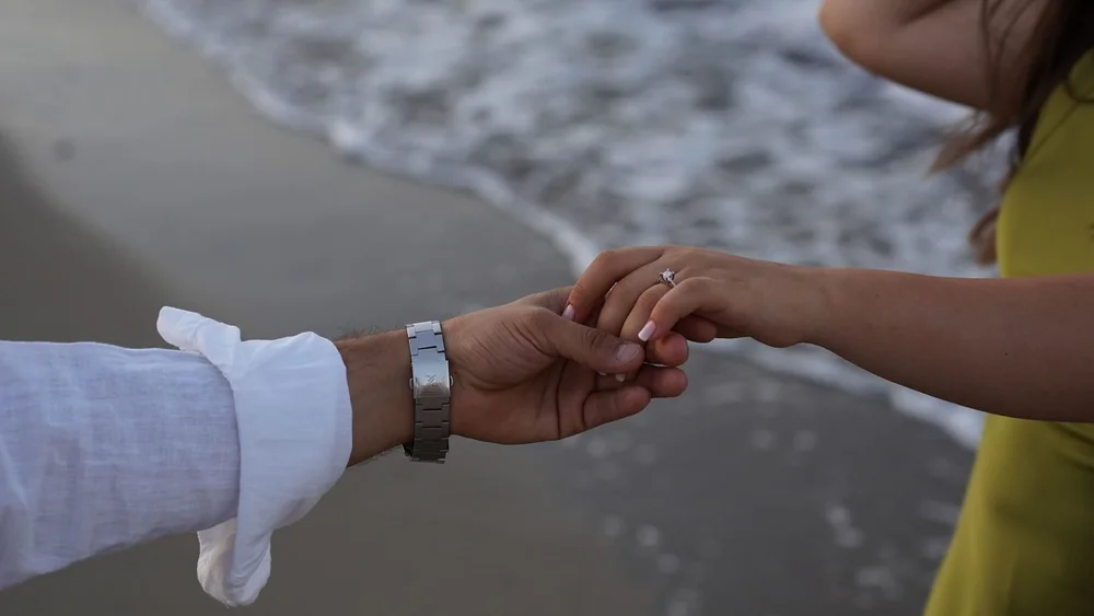 A couple getting engaged on the beach, discussing premarital counseling at Anchor Therapy.