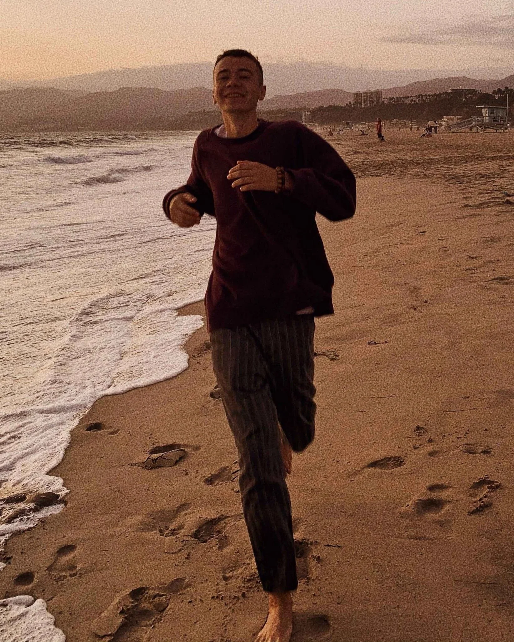 Teen running along the beach at sunset with main character energy in Hoboken