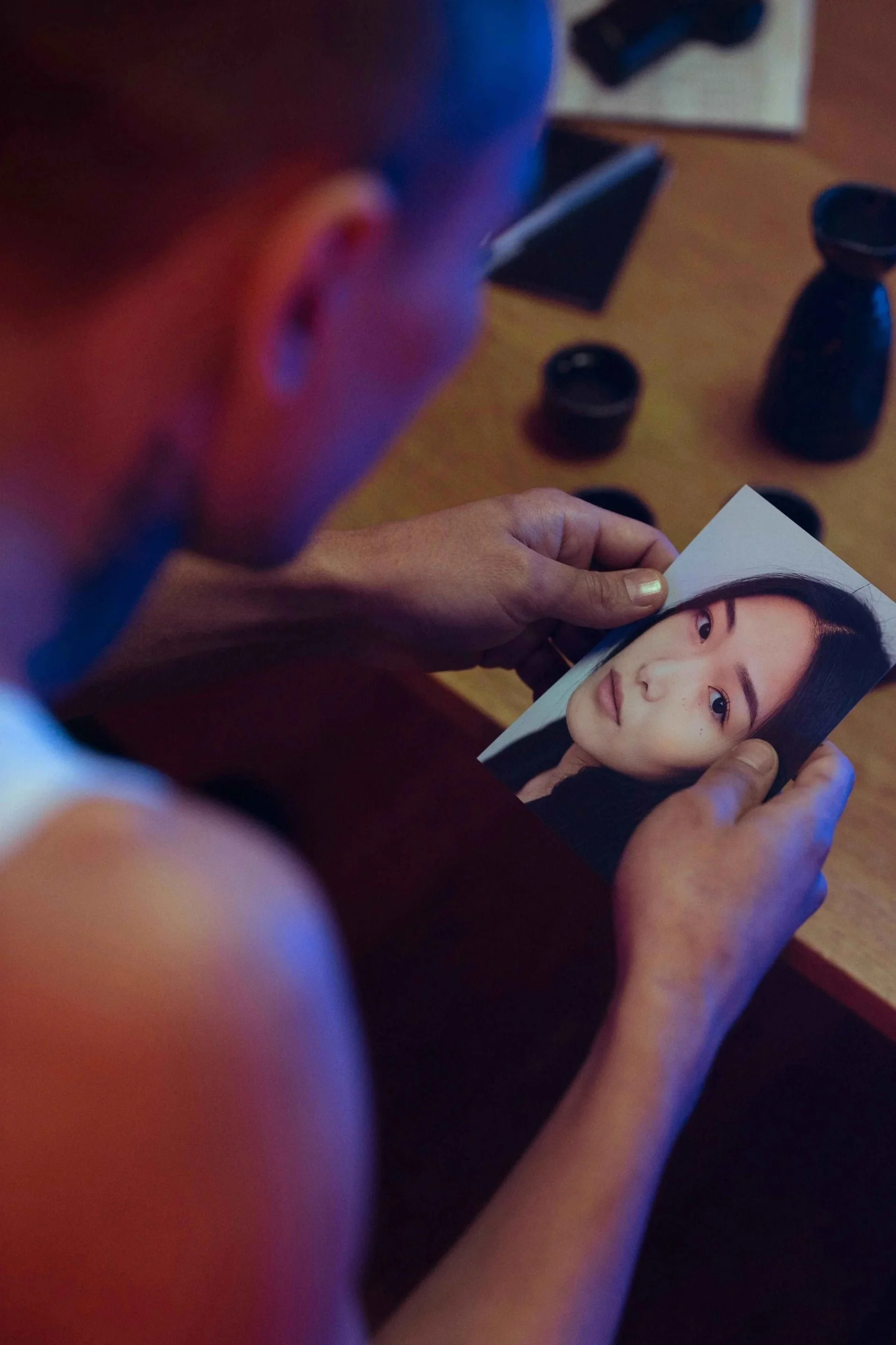 A man sitting alone holding a photo of his ex-girlfriend, struggling to cope with heartbreak and emotional pain after a breakup, supported by a Jersey City NJ therapist for men