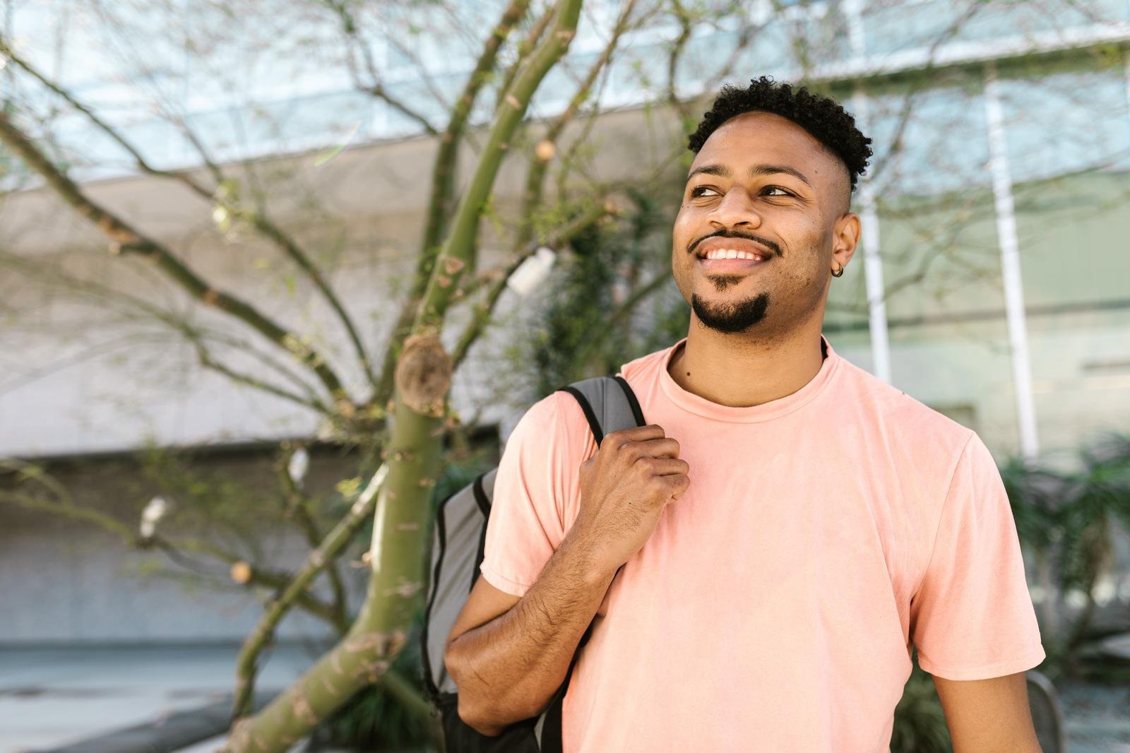 Smiling man wearing a backpack outdoors, an example of new possibilities after post traumatic growth, Hoboken NJ therapist