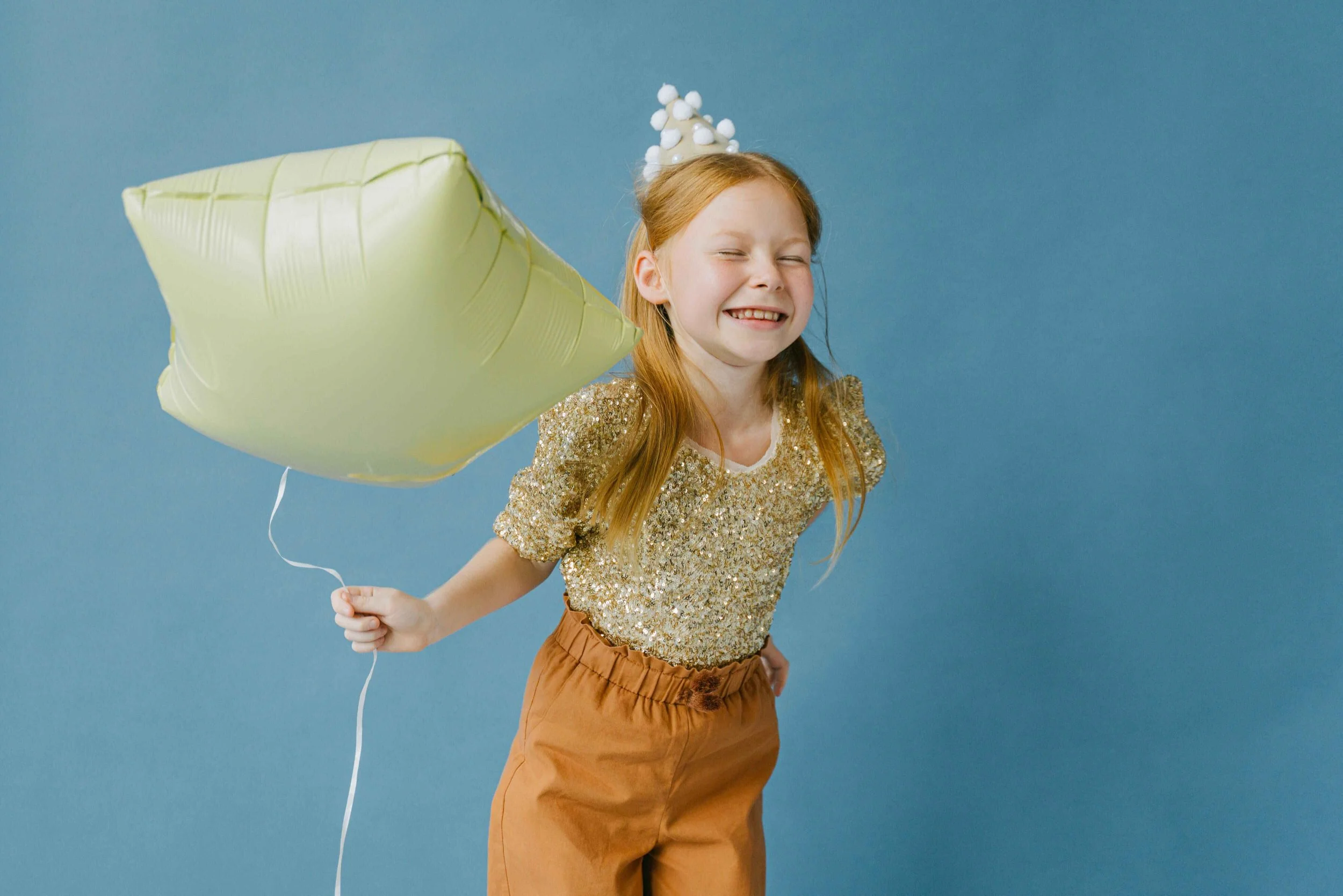 Girl in a gold sequin top and crown holding a balloon, golden child syndrome Hoboken NJ therapist