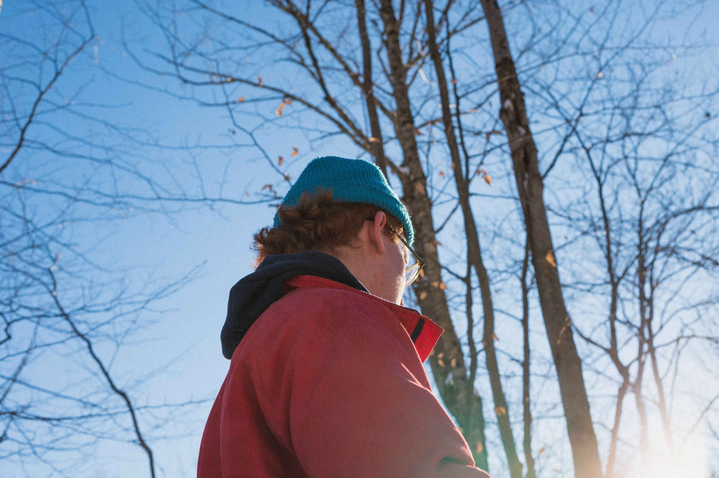 Man in a teal beanie looking up through bare winter trees, OCD therapy Hoboken NJ