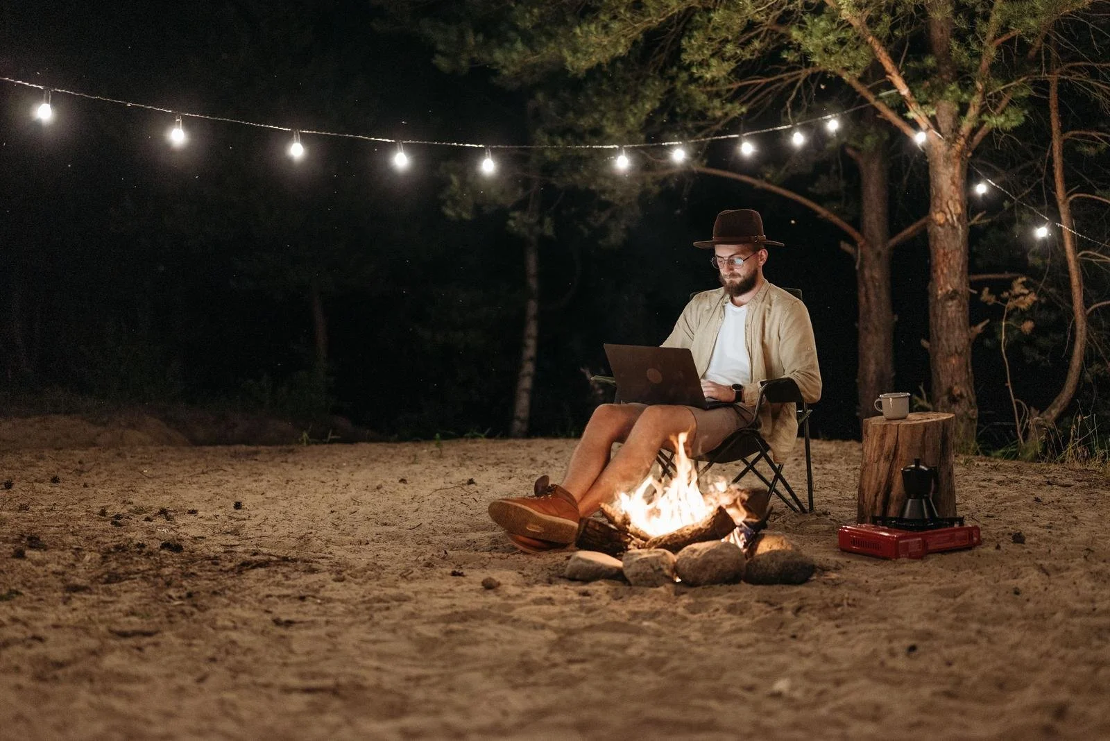 Man working on his laptop by a campfire at night, an example of the work-life integration extreme, Hoboken NJ therapist