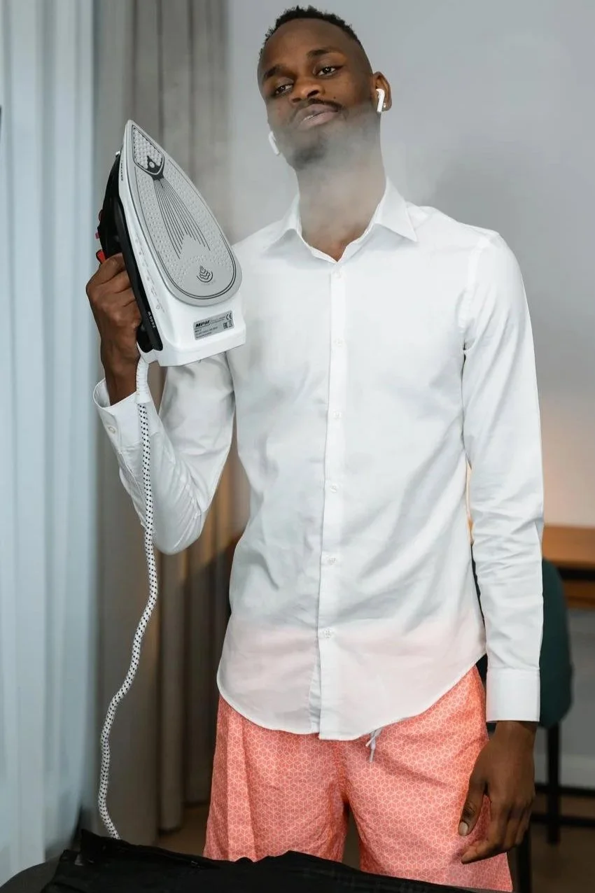 Man ironing his own shirt while listening to headphones, the opposite of weaponized incompetence in a family, Hoboken NJ therapist
