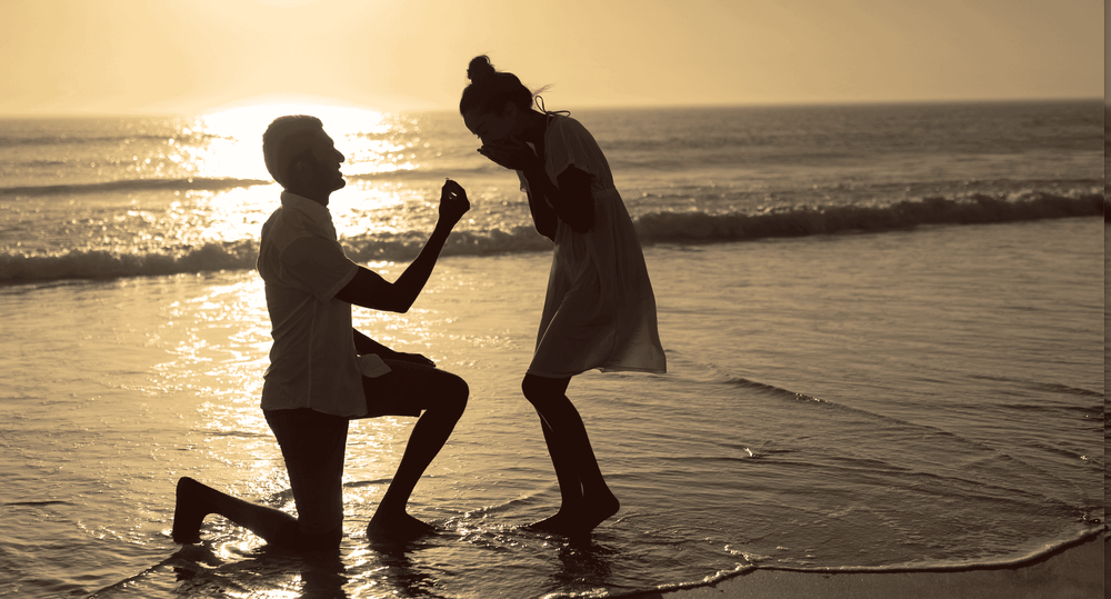 A couple getting engaged on the beach, discussing premarital counseling at Anchor Therapy.