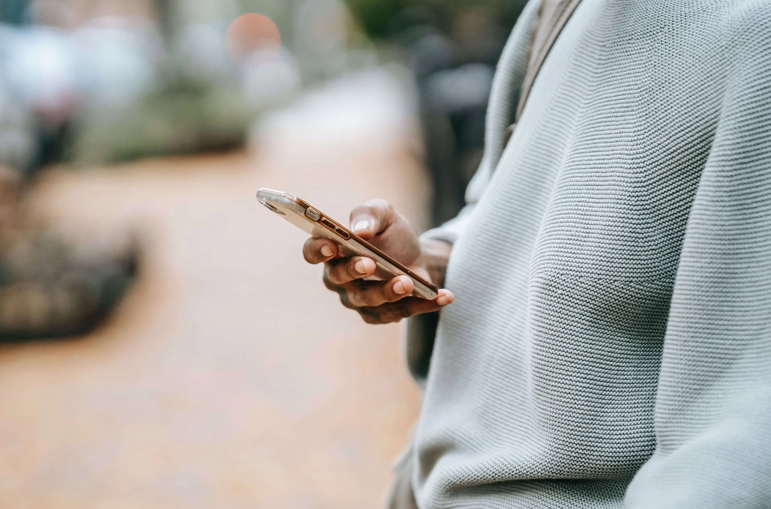 Person in a knit sweater checking their phone outdoors while recovering from love bombing with a Hoboken, NJ therapist