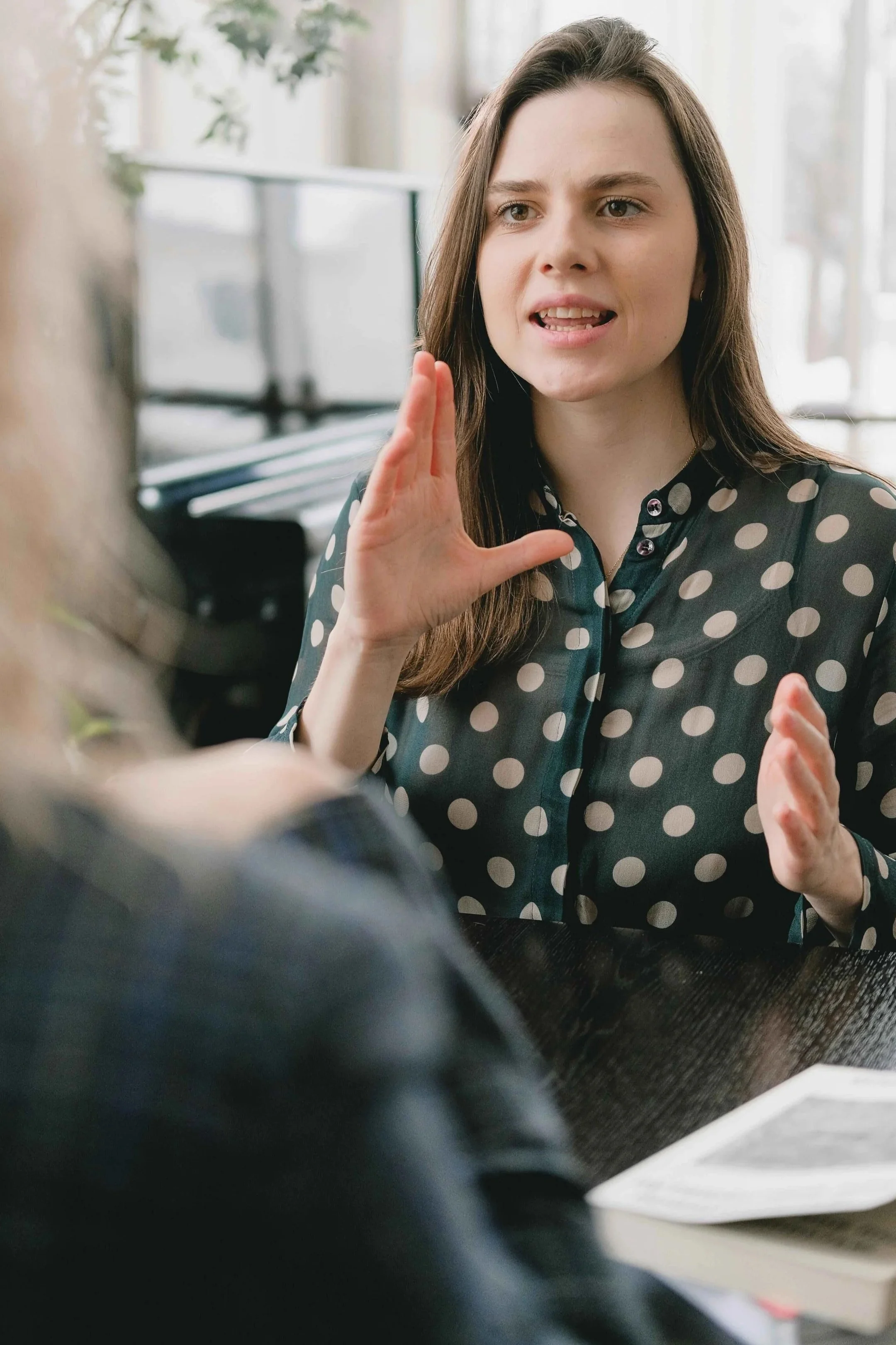Woman talking expressively with her hands during a serious conversation, illustrating communication anxiety, Hoboken NJ therapy