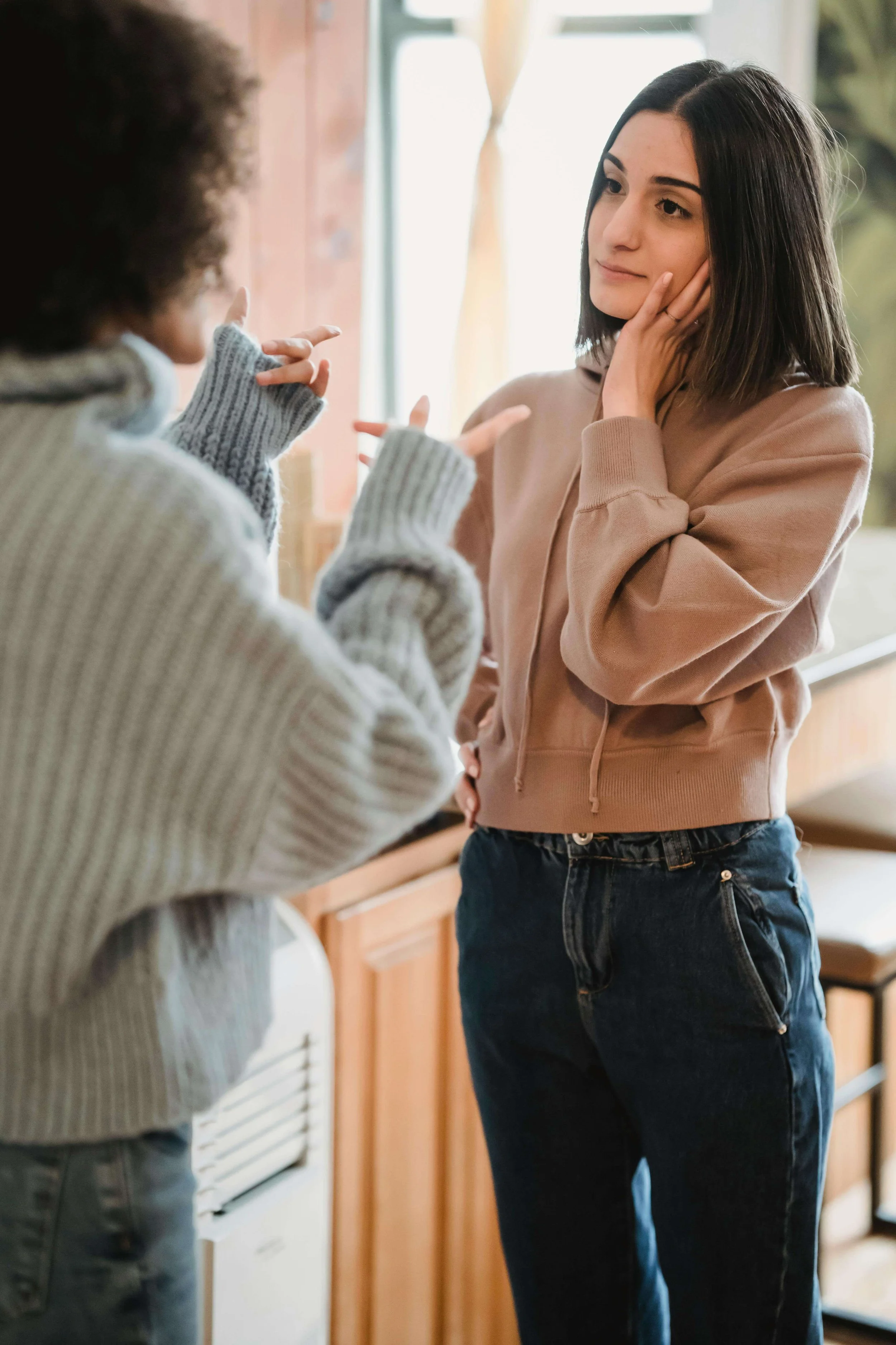 Two women in a tense conversation, one explaining the signs of being a family scapegoat, Hoboken NJ therapist