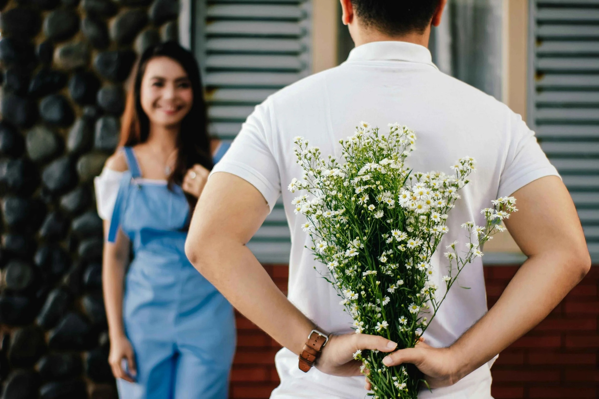 Man hiding a bouquet of flowers behind his back to surprise his girlfriend, love bombing signs Hoboken NJ therapist