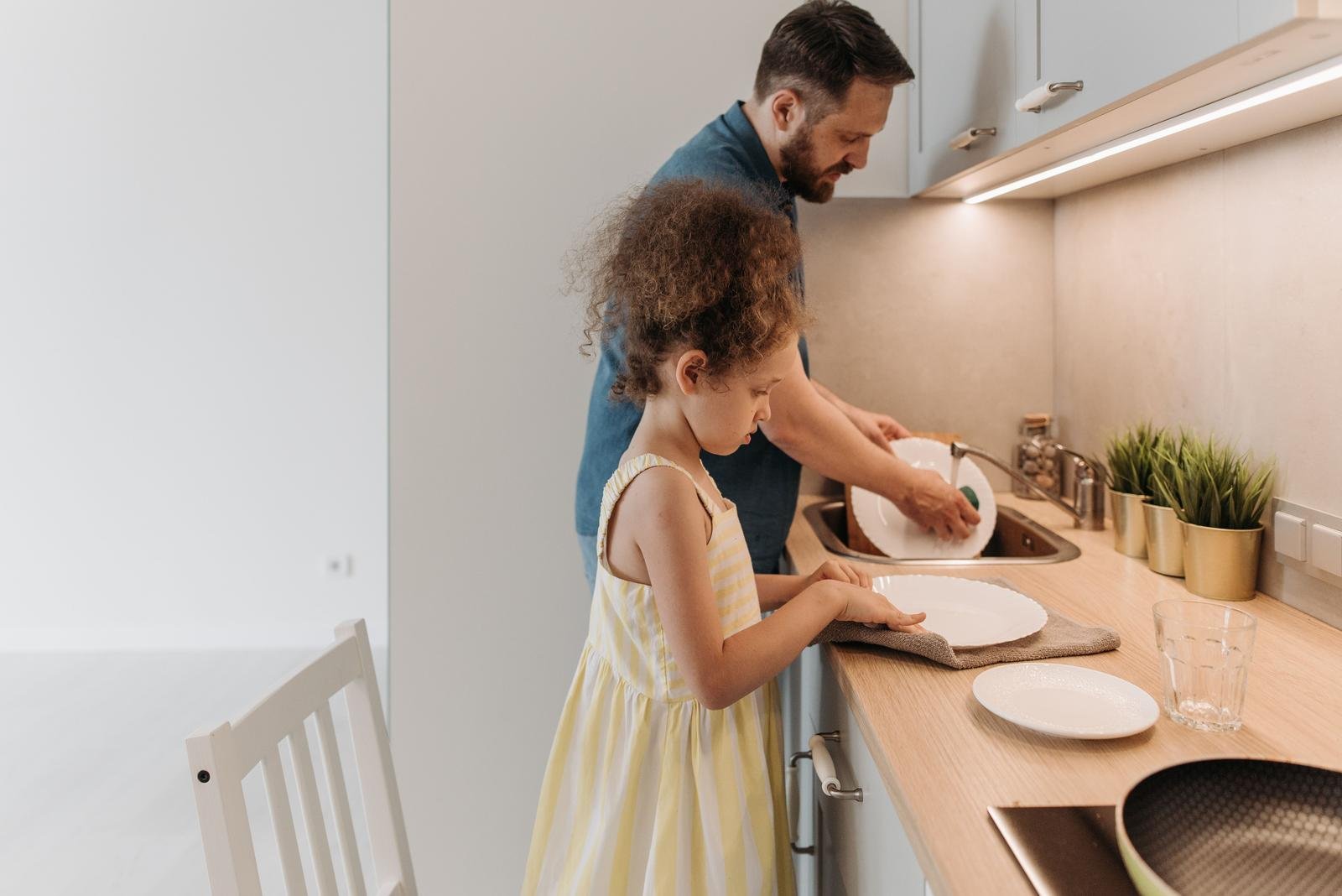 Father and daughter washing dishes together at the kitchen sink, sharing the load instead of weaponized incompetence, family counseling Hoboken NJ