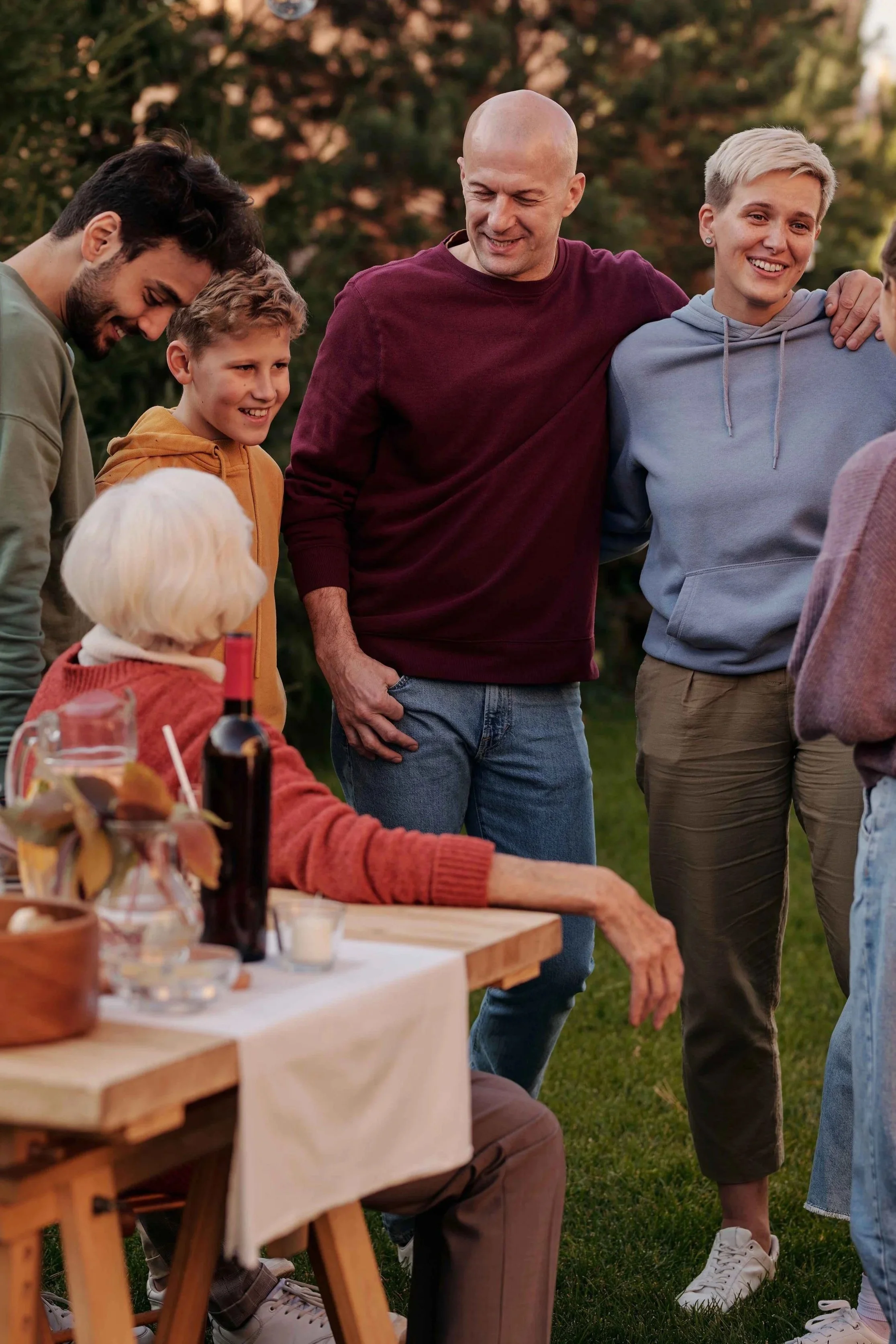 Extended family standing closely together with arms around each other at an outdoor gathering, an example of a family that looks warm on the surface, Hoboken NJ therapist