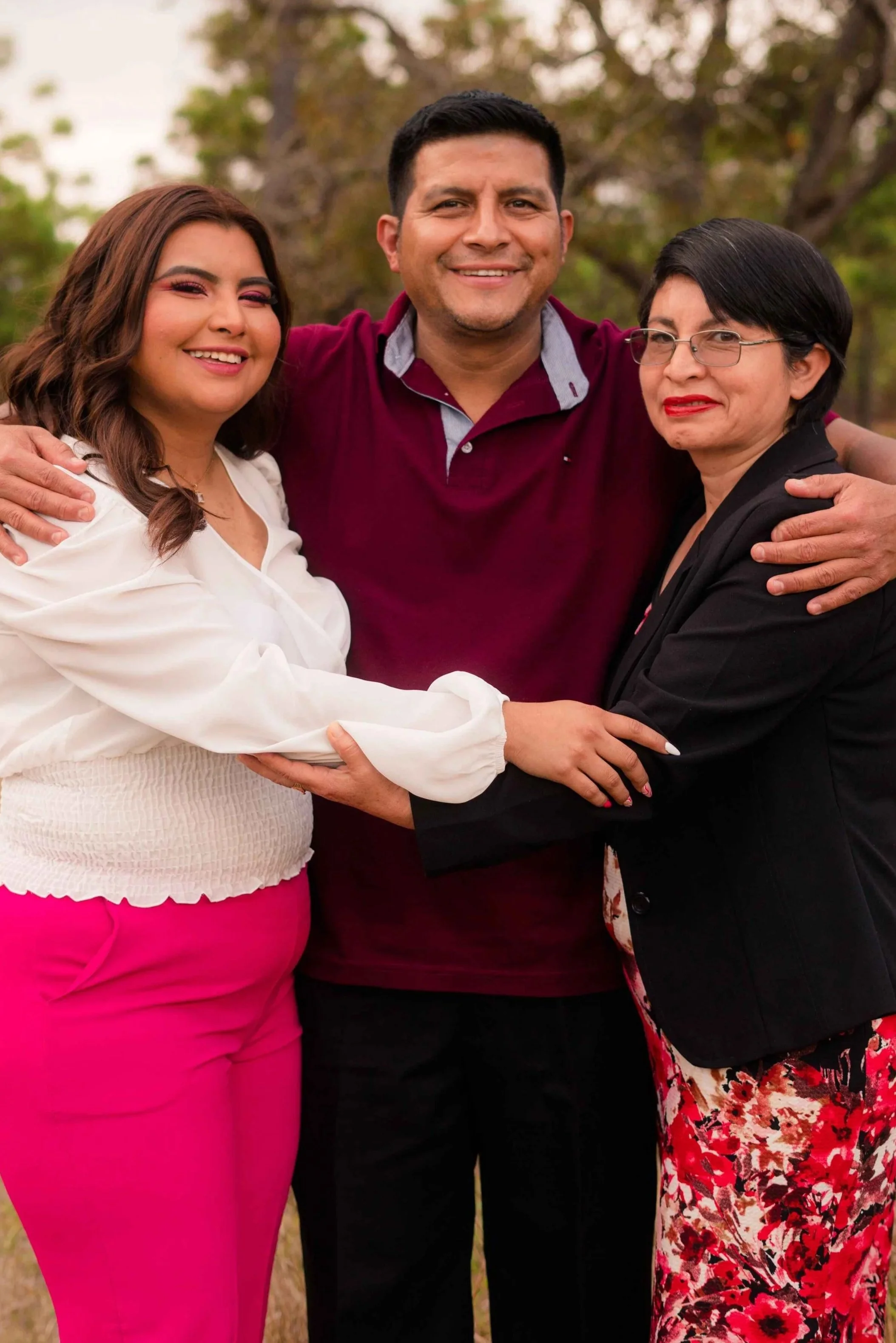 Three family members posing arm-in-arm standing very close together, an example of the closeness that can look identical to enmeshment from the outside, Hoboken NJ therapist