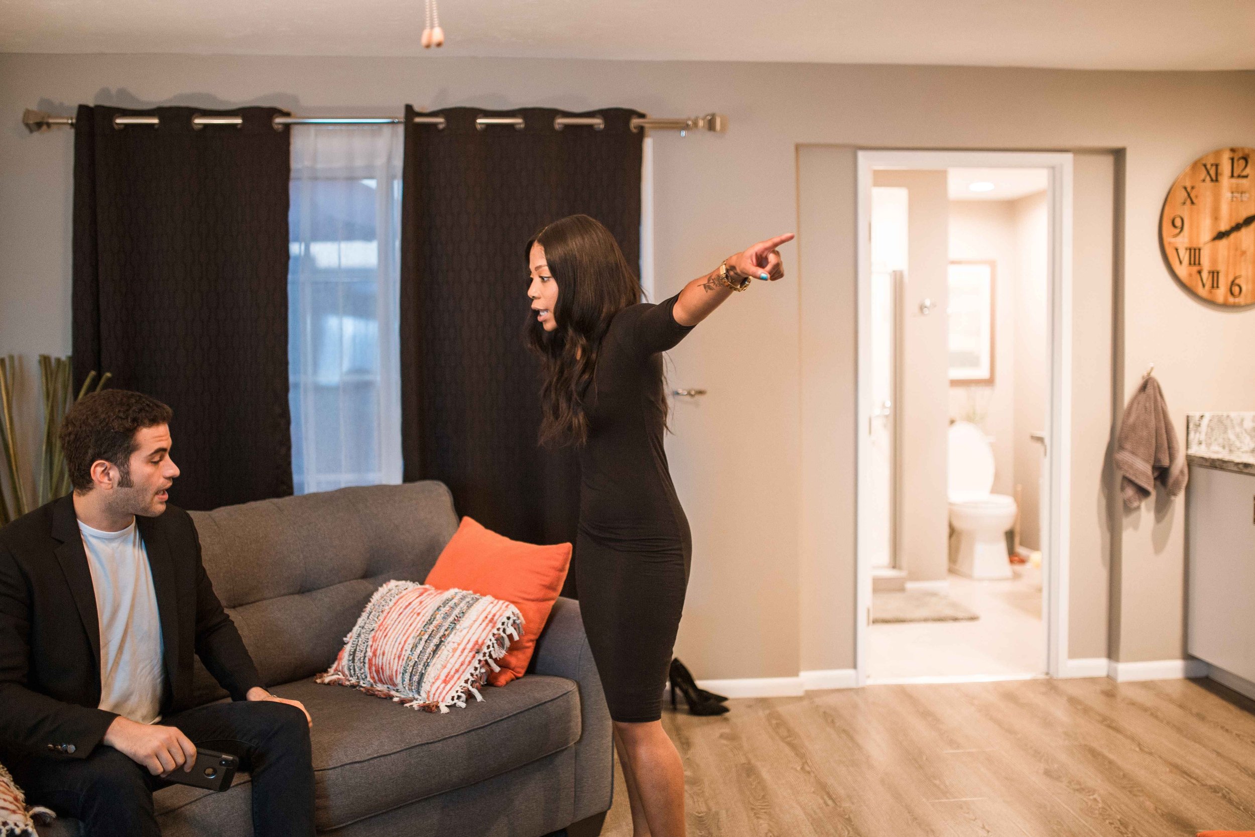 Woman pointing toward the door while a seated man holds his phone during a tense breakup, illustrating narcissist hoovering, Hoboken NJ therapist