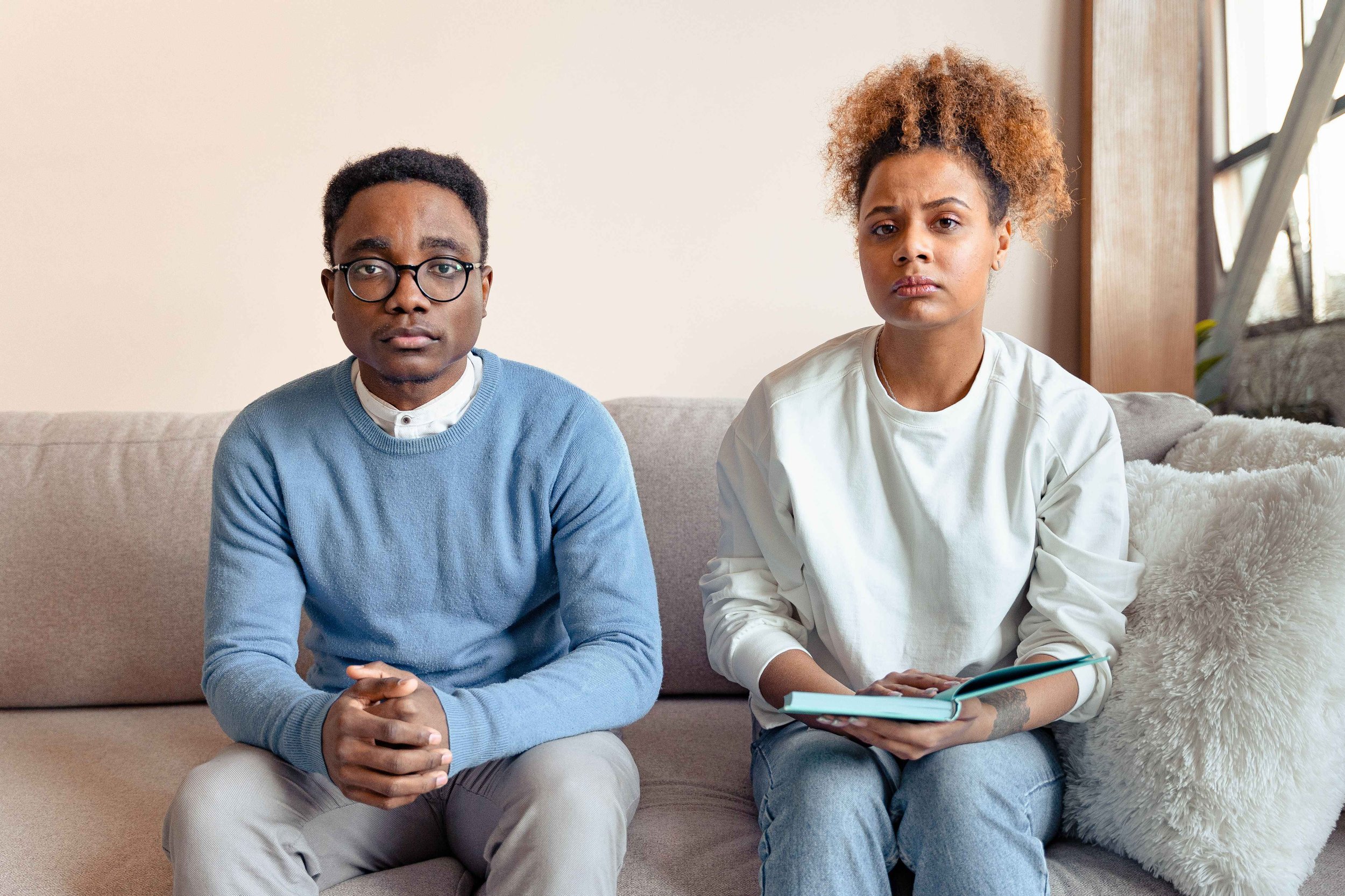 Couple sitting emotionally distant on a couch after future faking strained the relationship, Hoboken NJ therapist