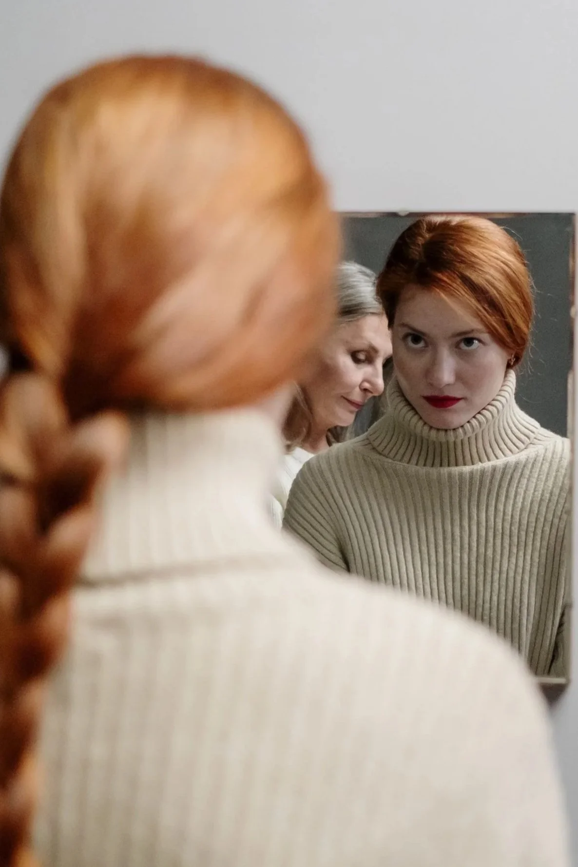 Woman looking in a mirror and seeing an older woman's reflection beside her own, adult children of narcissistic parents Hoboken NJ therapist